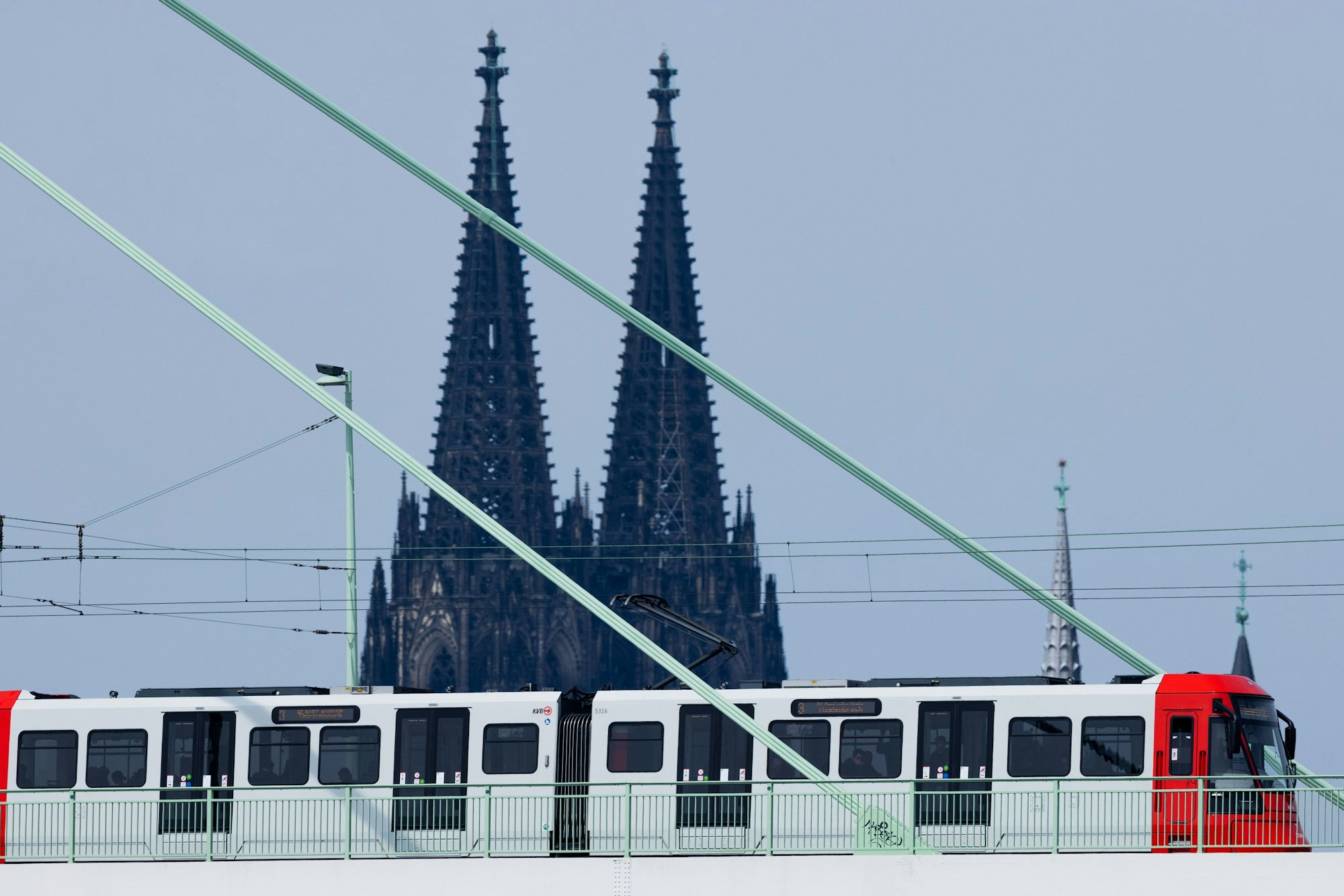 Eine Straßenbahn der Kölner Verkehrsbetriebe (KVB) fährt über die Severinsbrücke vor der Kulisse des Kölner Doms.