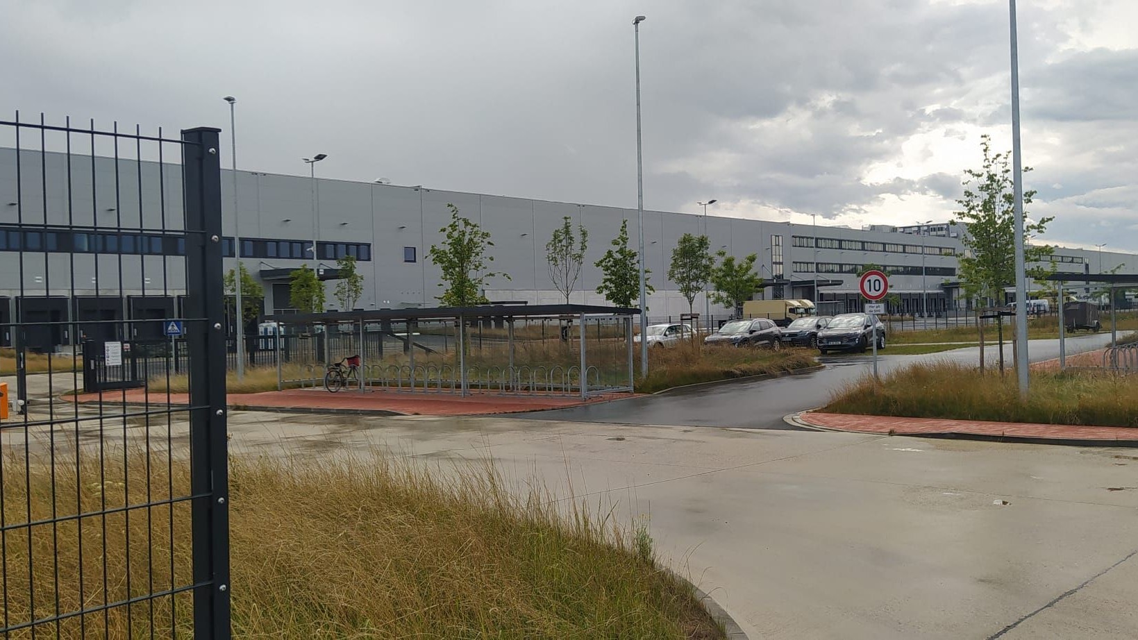 Junge Bäume stehen vor einem neuen, ganz in grau gehaltenen Industriegebäude.