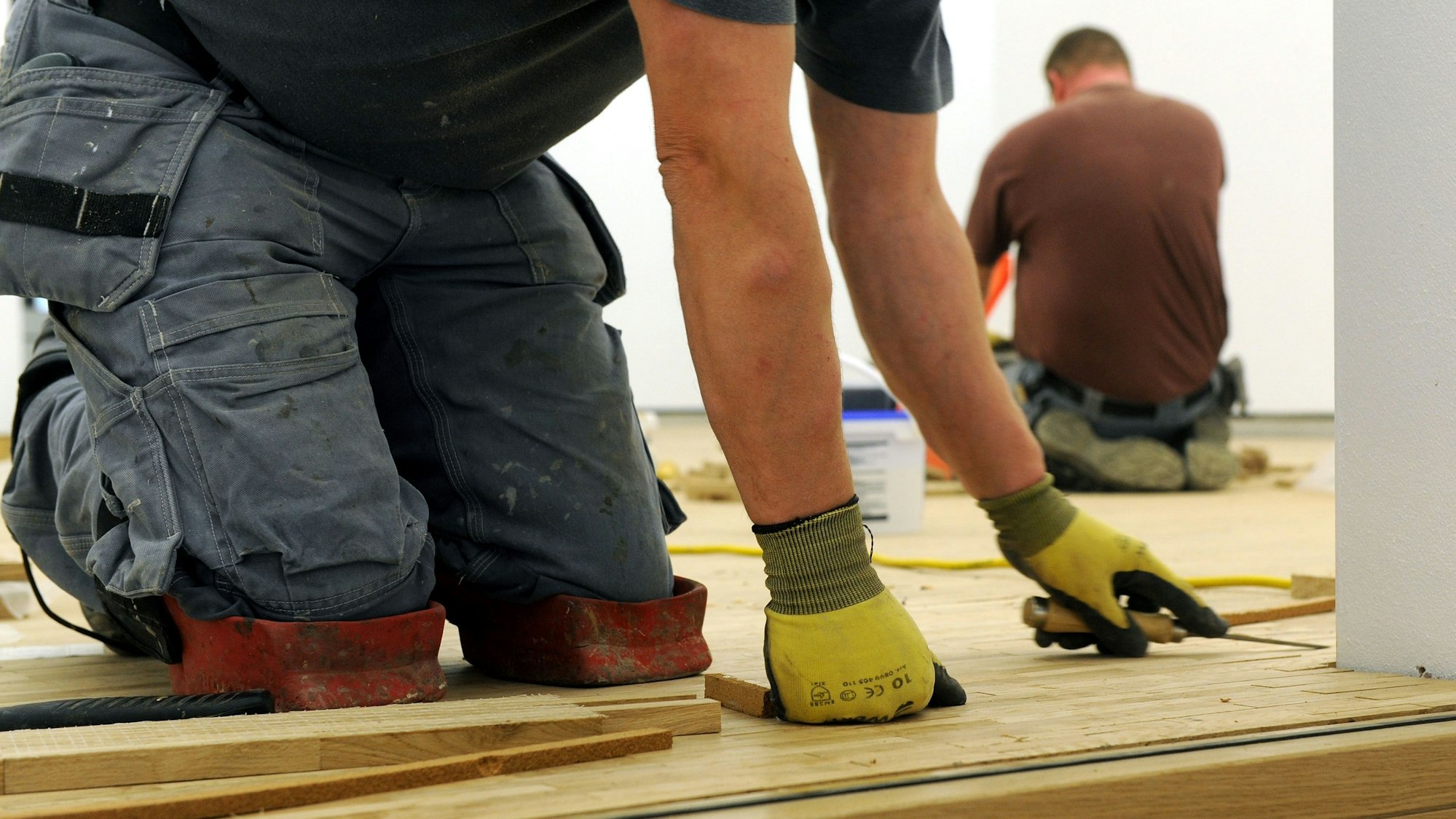 Handwerker verlegen einen Parkettboden.