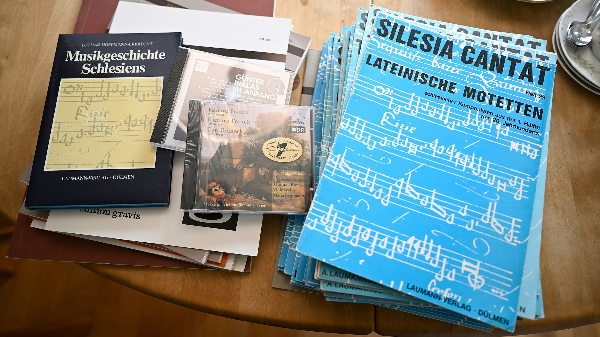 Auf einem Tisch liegen blaue Notenhefte, CDs und Bücher.