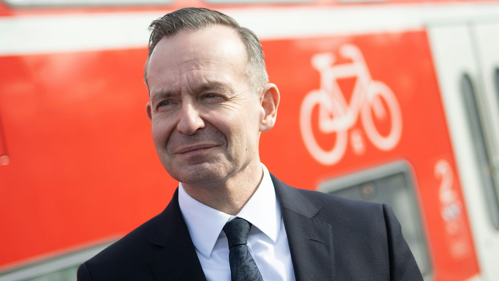 Volker Wissing steht während einer Besichtigung der Bahnstrecke Mannheim-Frankfurt am Bahnhof Lampertheim neben dem Fahrradabteil eines Regional-Expresses.