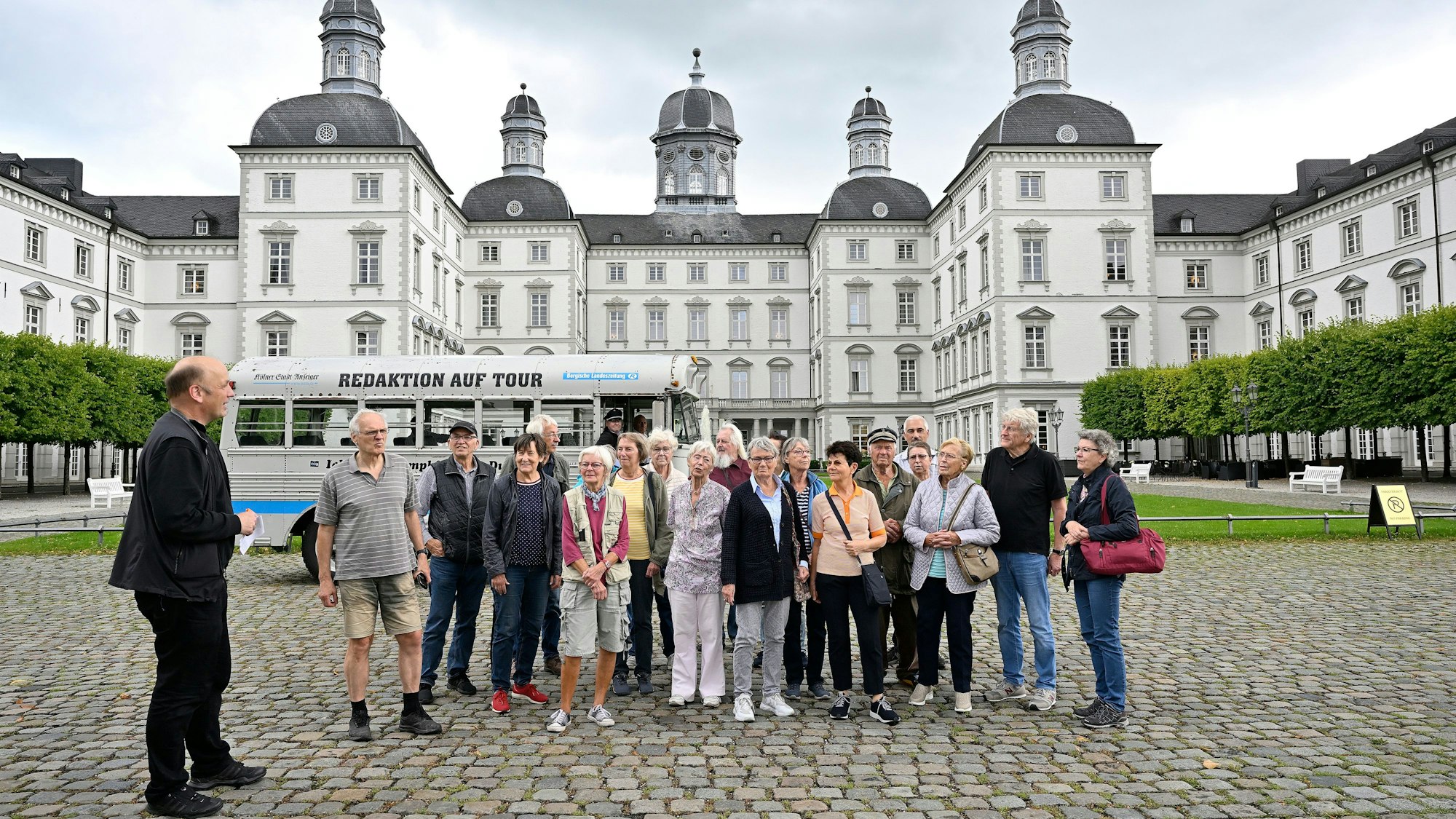 Eine Gruppe und ein  historischer Bus stehen im Innenhof von Schloss Bensberg.
