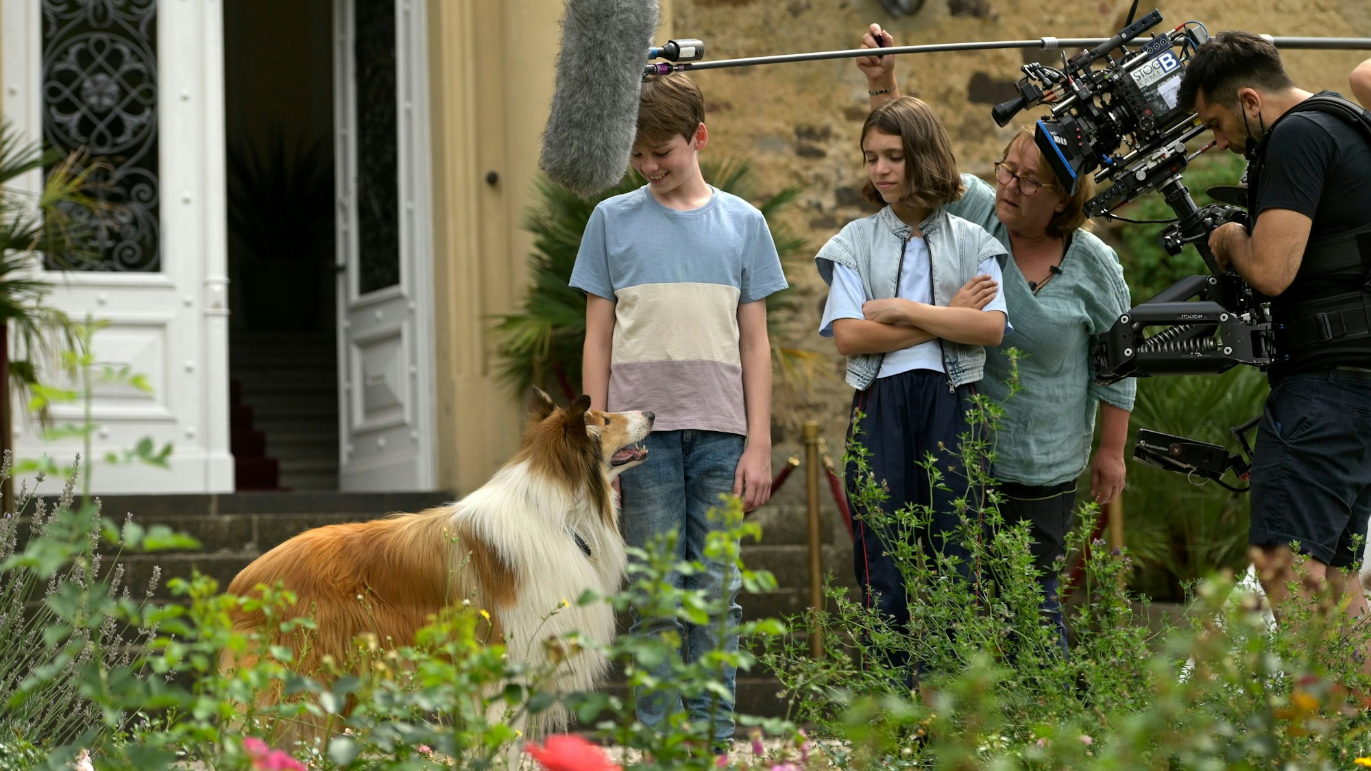 Auf dem Bild sind Lassie und weitere Beteiligte beim Filmdreh in Ringsheim zu sehen. Sie stehen im Garten der Burg.
