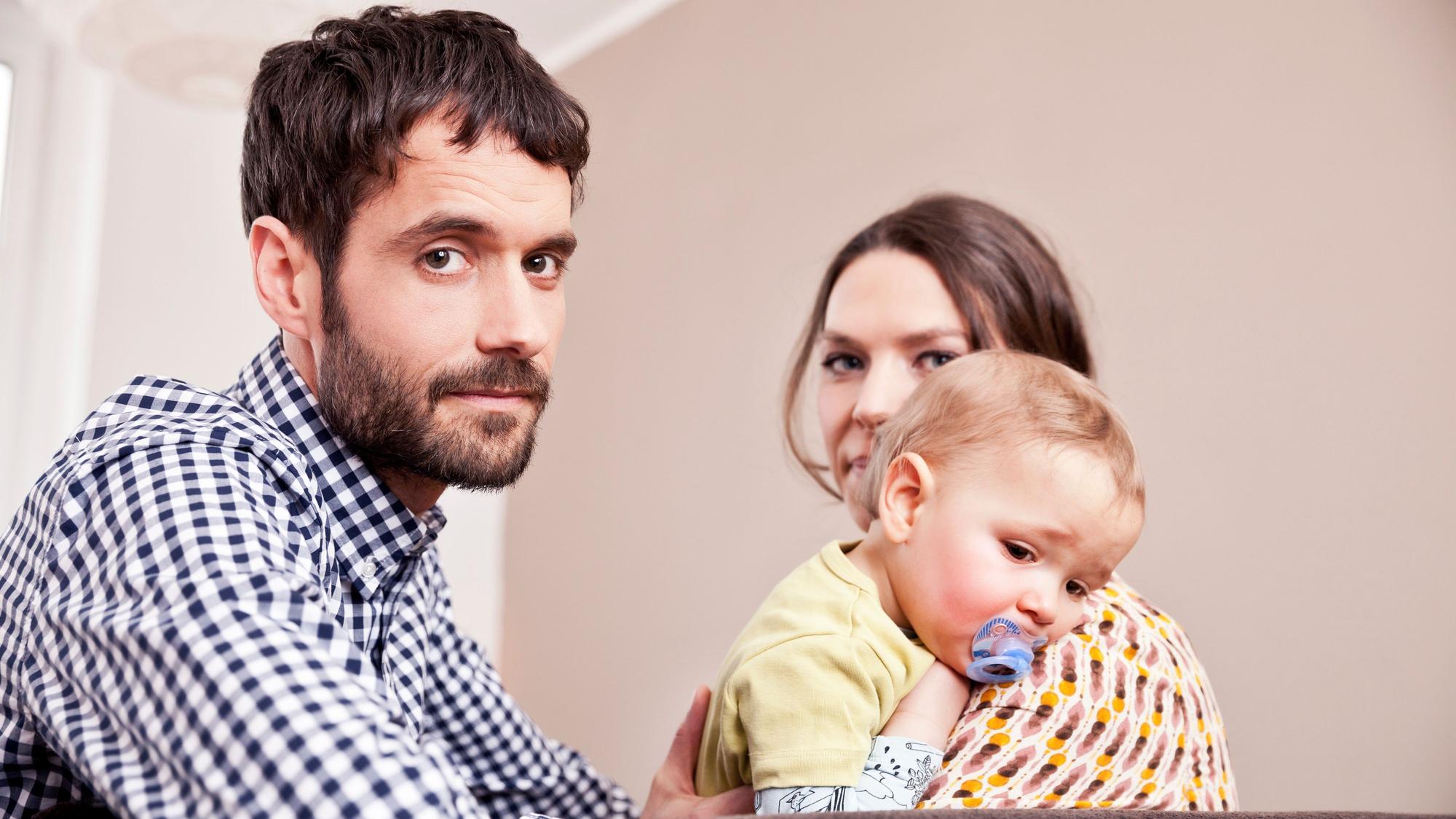 Vater, Mutter und Kind blicken gestresst