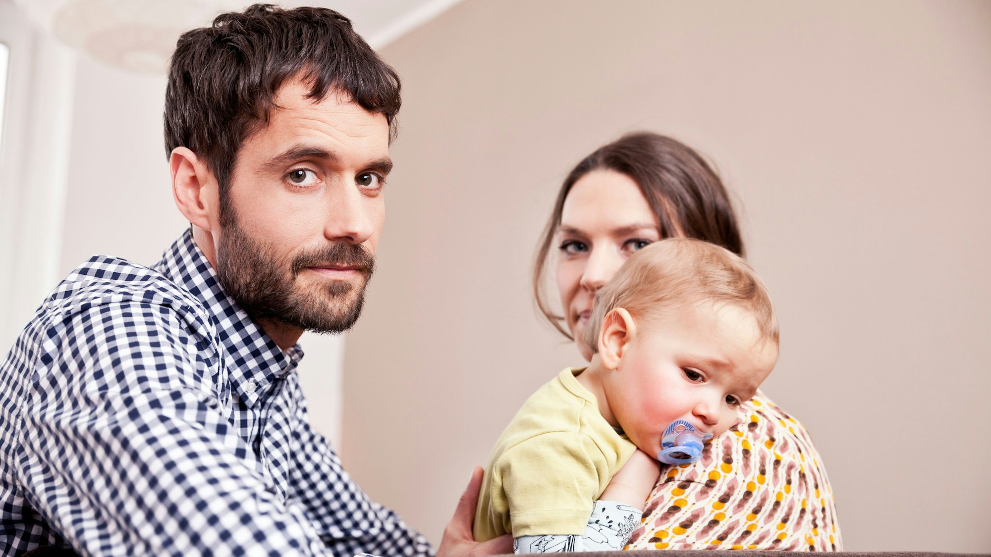 Vater, Mutter und Kind blicken gestresst