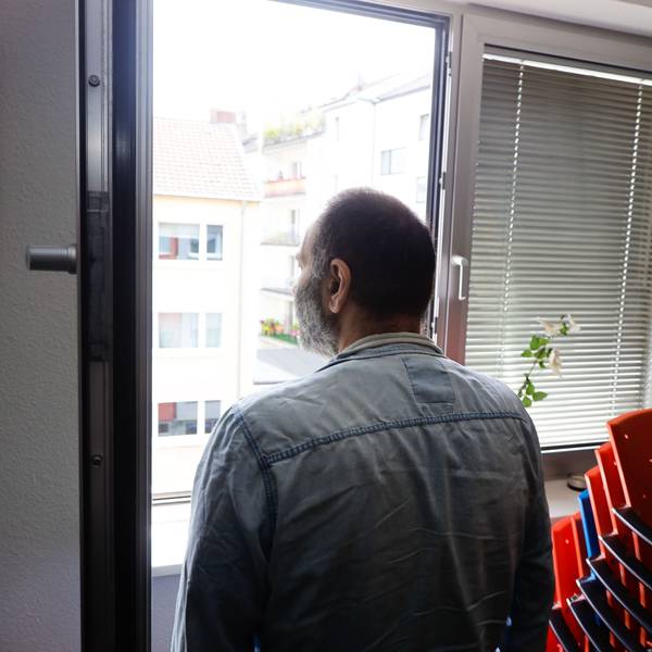 Langzeit-Cannabis-Konsument steht am Fenster eines Raums der Drogenhilfe Köln, Rückenansicht.