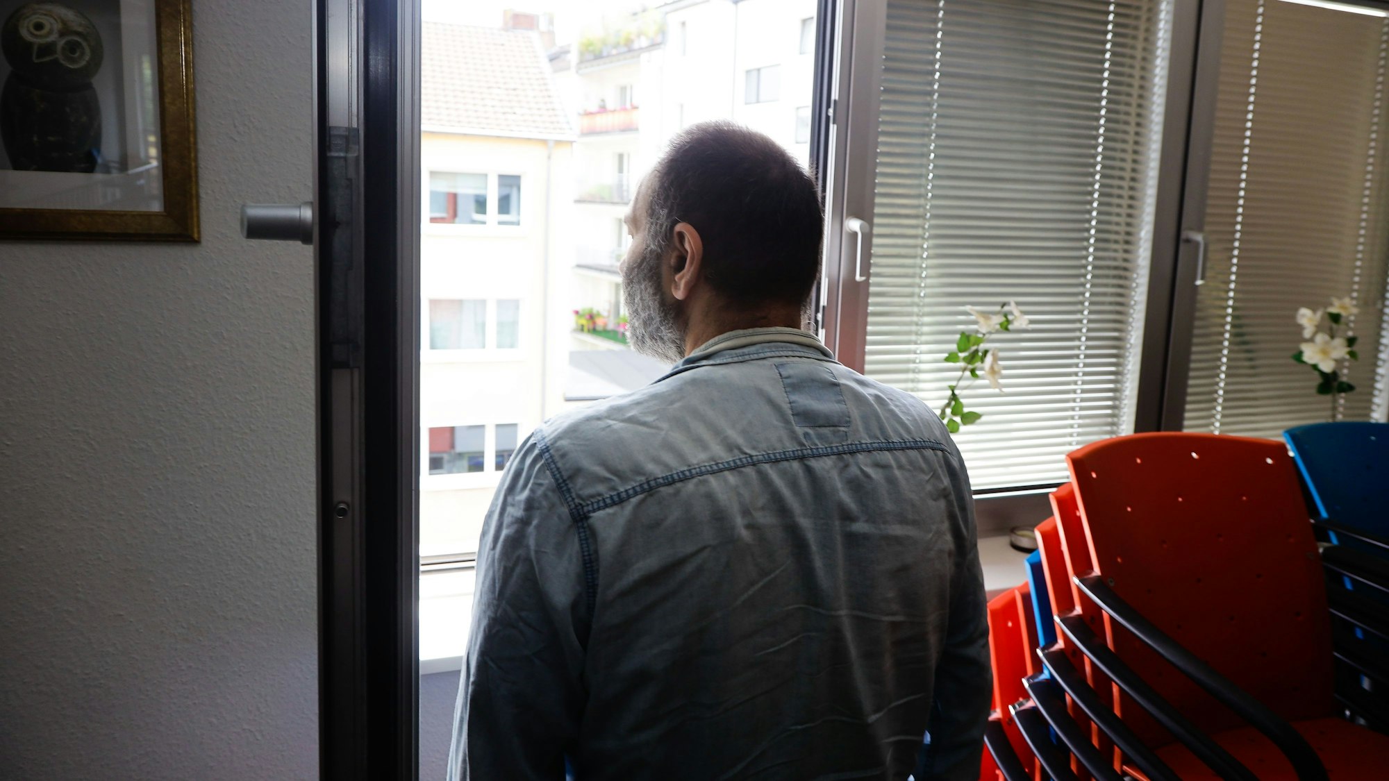 Langzeit-Cannabis-Konsument steht am Fenster eines Raums der Drogenhilfe Köln, Rückenansicht.
