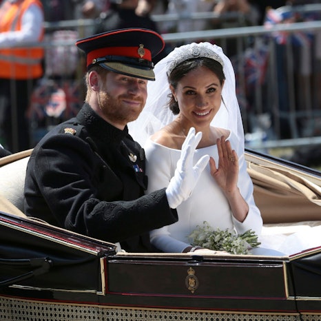 Bräutigam Prinz Harry und seine Braut Herzogin Meghan fahren nach ihrer Hochzeit in einer Kutsche und winken Menschen zu.