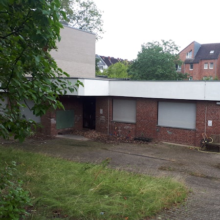 Ein Flachbau mit roten Klinkern und heruntergelassenen Rollläden ist zu sehen.