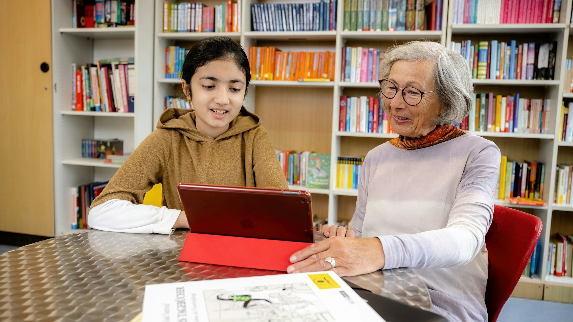 Leselernhelferin Elisabeth Wolf übt lesen am Tablet mit ihrem Schützling Rojin.