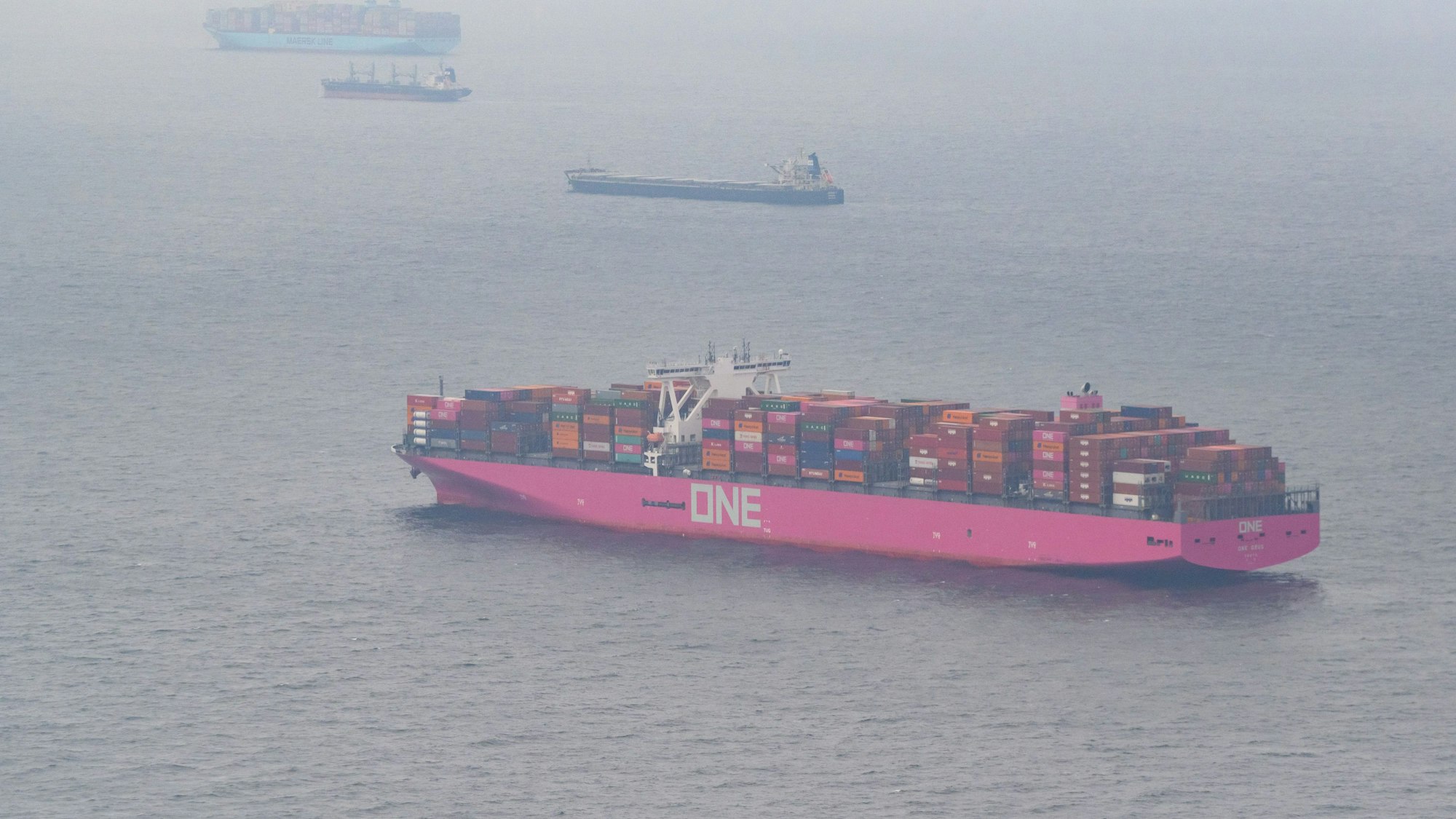 Der mit Containern beladene Frachter One Grus (v) liegt vor Anker in der Nordsee. Dahinter ankern die Grandt, ein Schüttgutfrachter, die Celsius Portsmouth, ein Chemietanker und die Mary Maersk, ein weiteres Containerschiff.