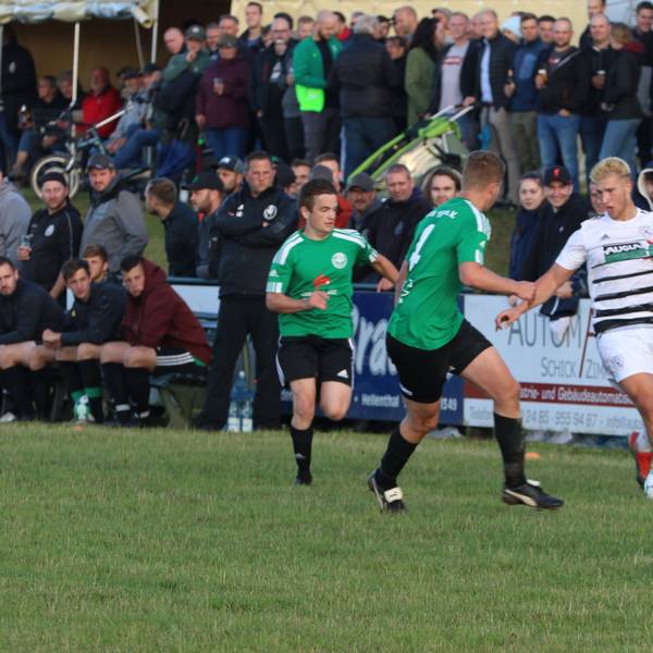 Ein Erftstädter Spieler kontrolliert, bedrängt von zwei Spielern aus Schöneseiffen, den Ball. Im Hintergrund sind die Zuschauer zu sehen.
