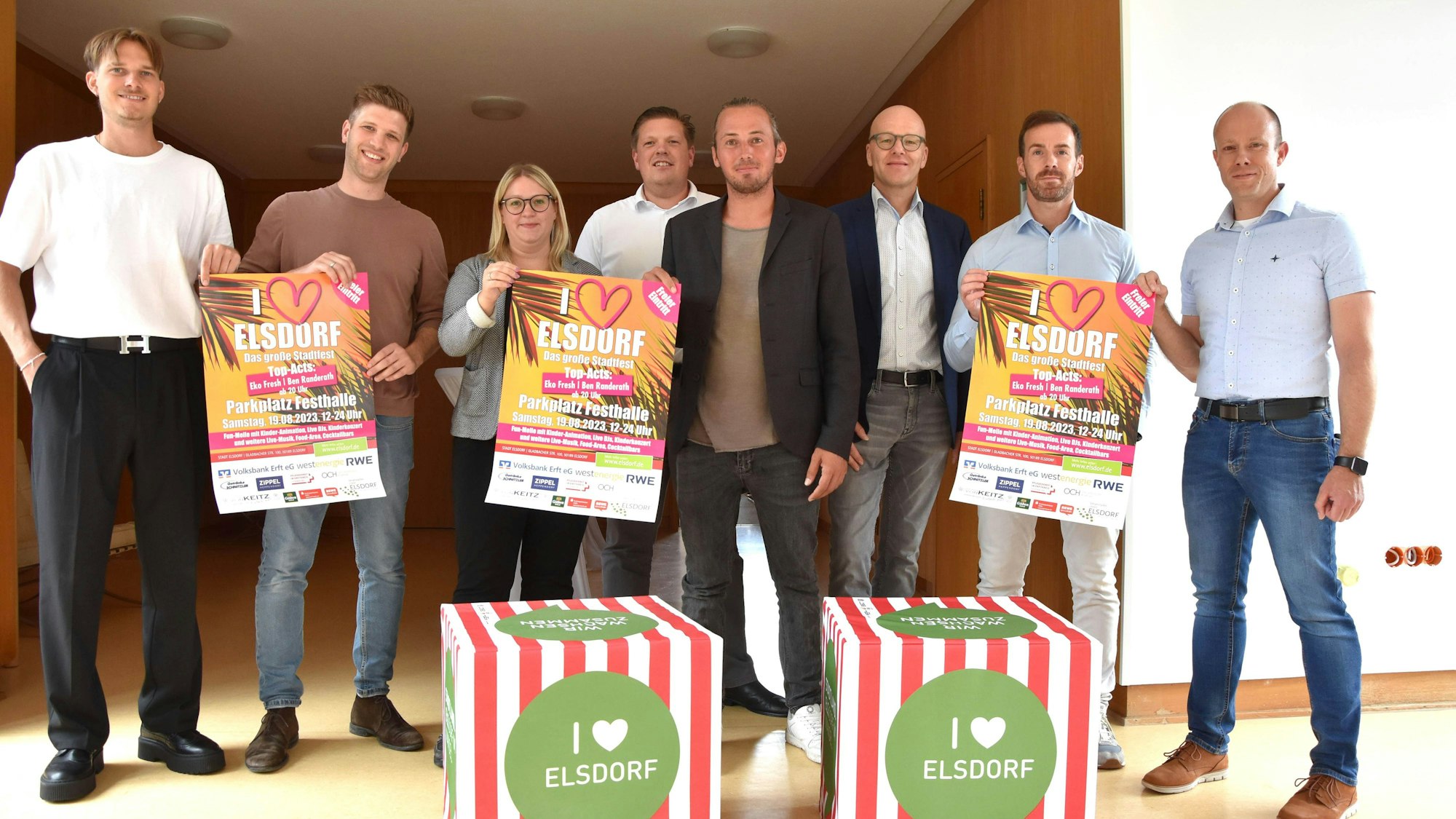 Mitarbeiter der Elsdorfer Verwaltung halten Plakate des Stadtfestes hoch.