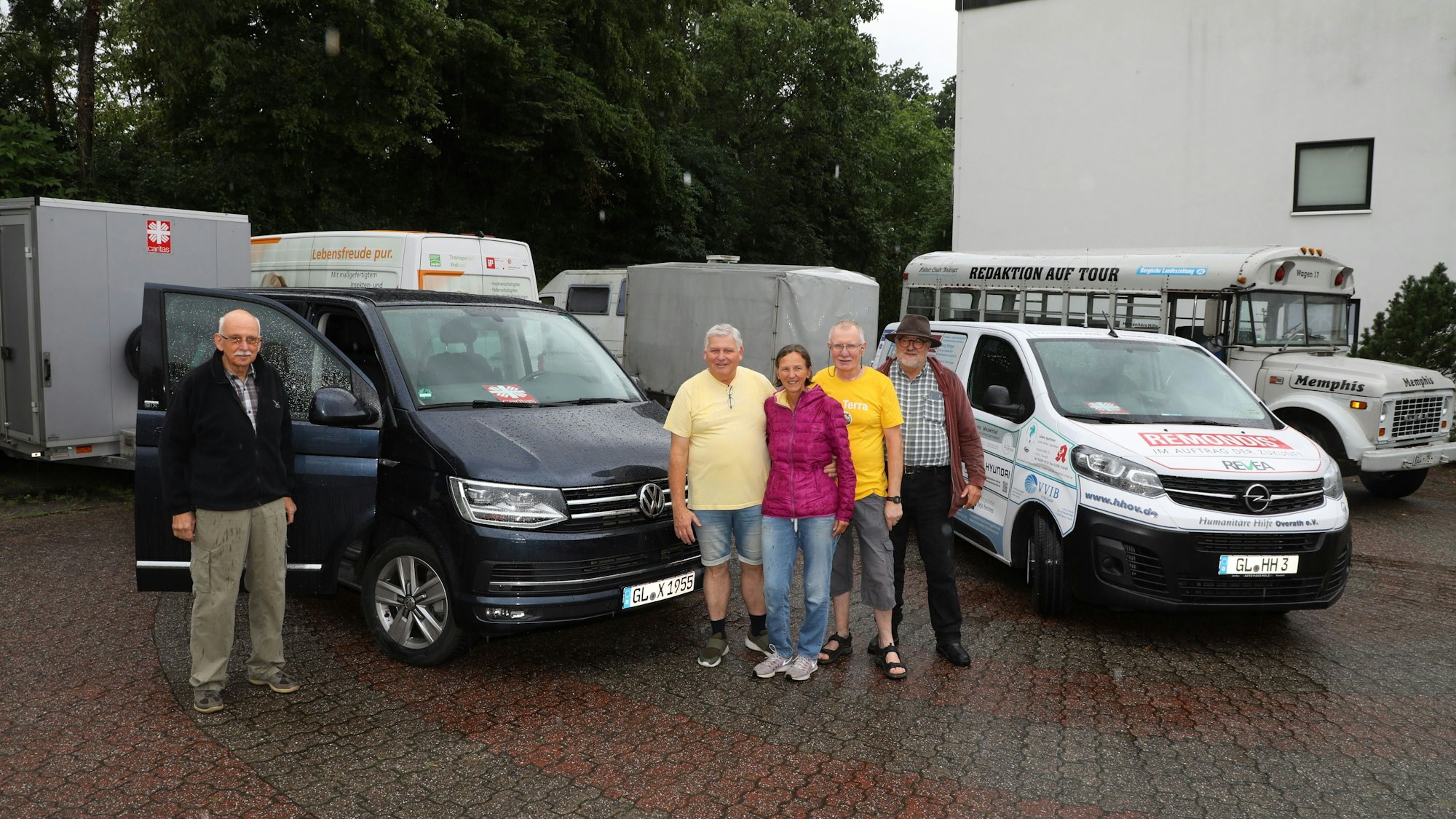 Menschen stehen vor zwei Pkw-Gespannen, die mit Hilfsgütern für Litauen beladen sind.