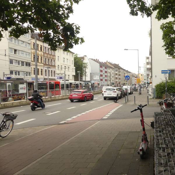 Eine zweispurige Straße mit einer Straßenbahnhaltestelle in der Mitte ist zu sehen. Im Vordergrund steht das Schild der Senioreneinrichtung, die unmittelbar an der Straße liegt.