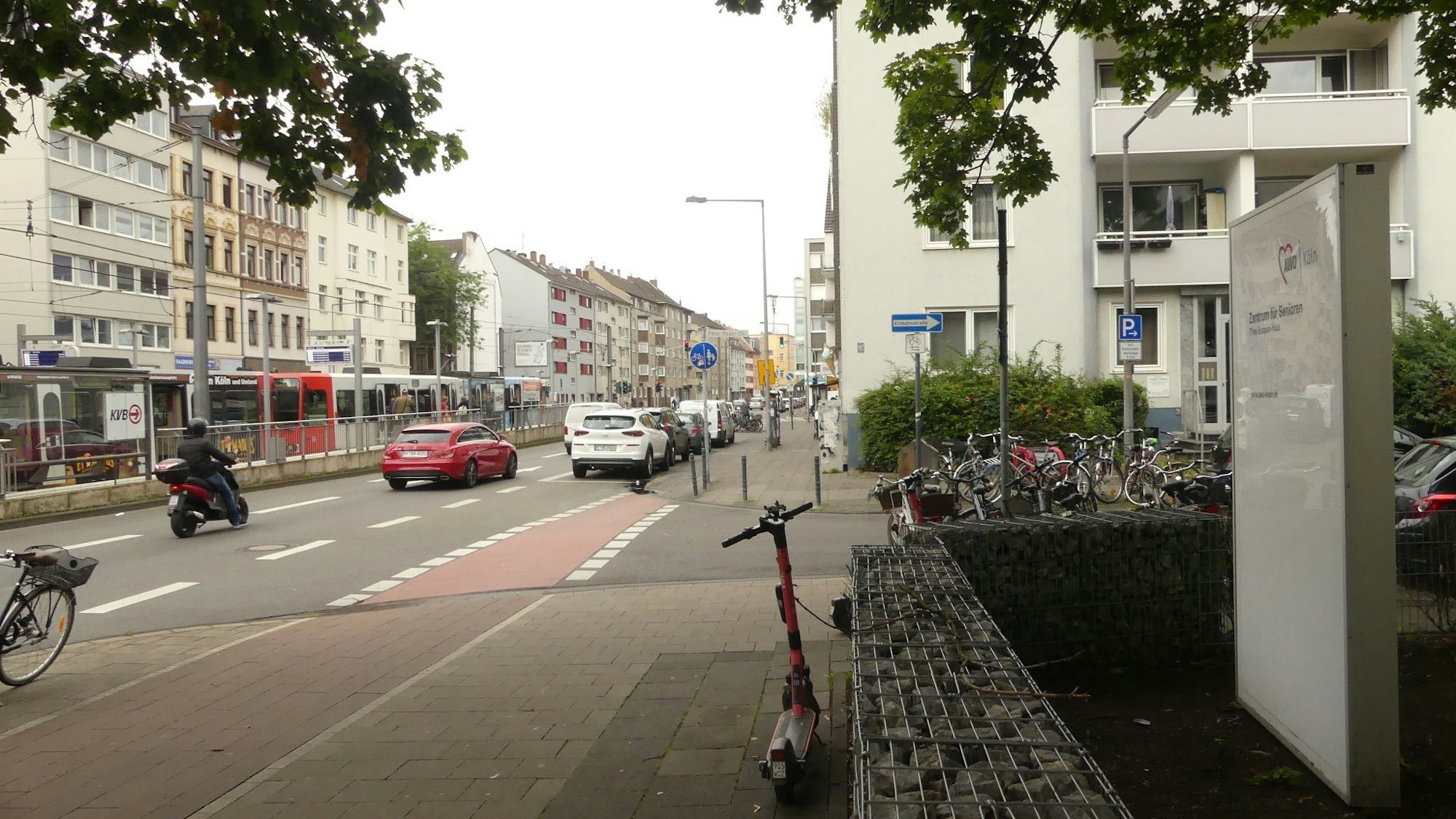Eine zweispurige Straße mit einer Straßenbahnhaltestelle in der Mitte ist zu sehen. Im Vordergrund steht das Schild der Senioreneinrichtung, die unmittelbar an der Straße liegt.