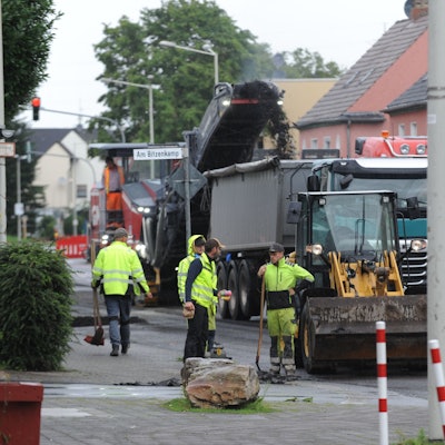 Baumaschinen sind auf einer teilweise abgefrästen Fahrbahn zugange.