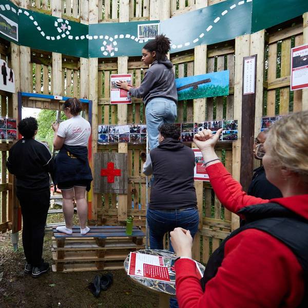 Junge Rotkreuzler verzieren Bretterwände mit Bildern.