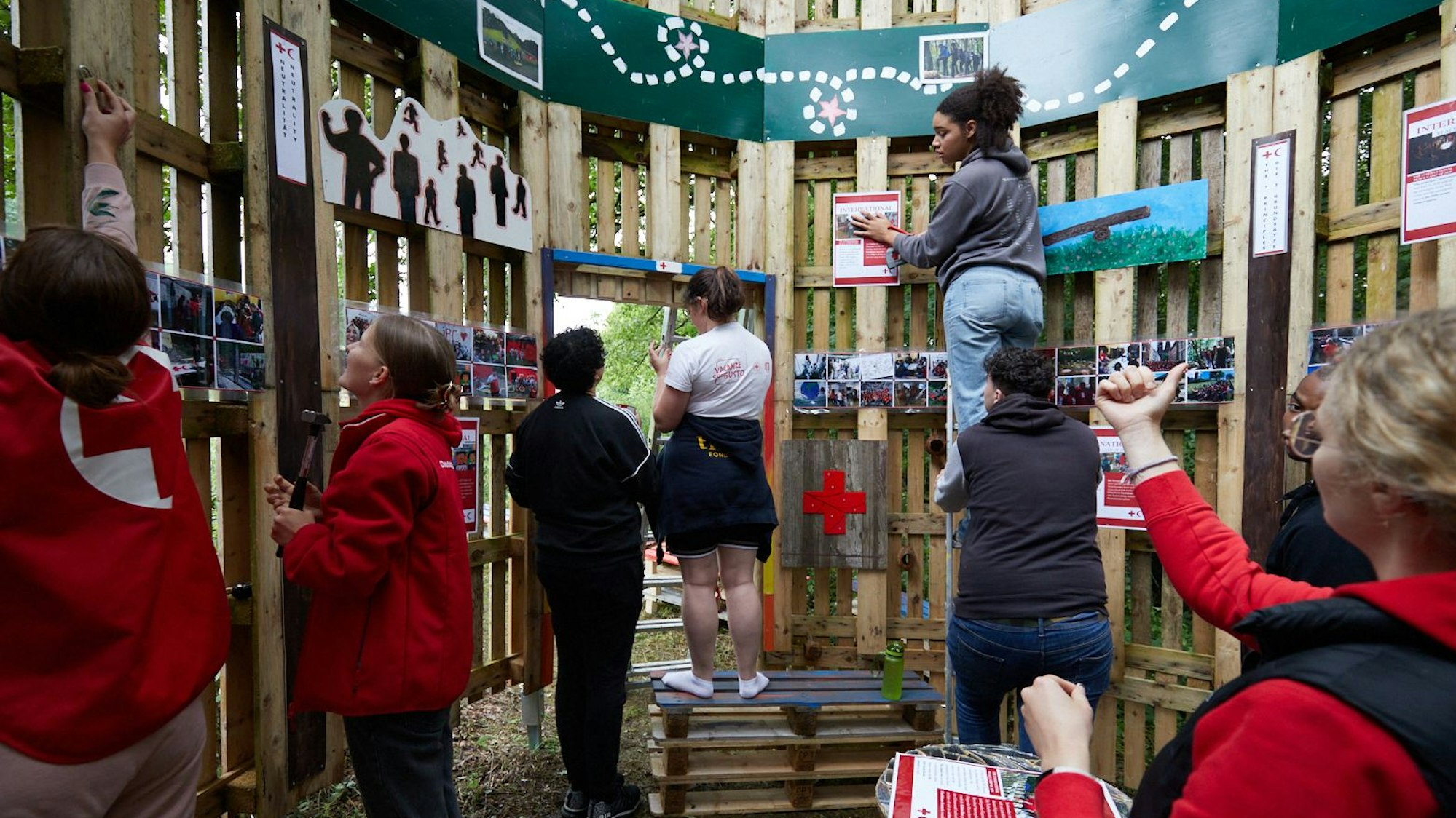 Junge Rotkreuzler verzieren Bretterwände mit Bildern.