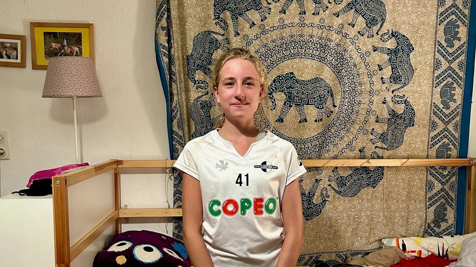 Mona Görtz steht in ihrem Kinderzimmer. Sie guckt in die Kamera.