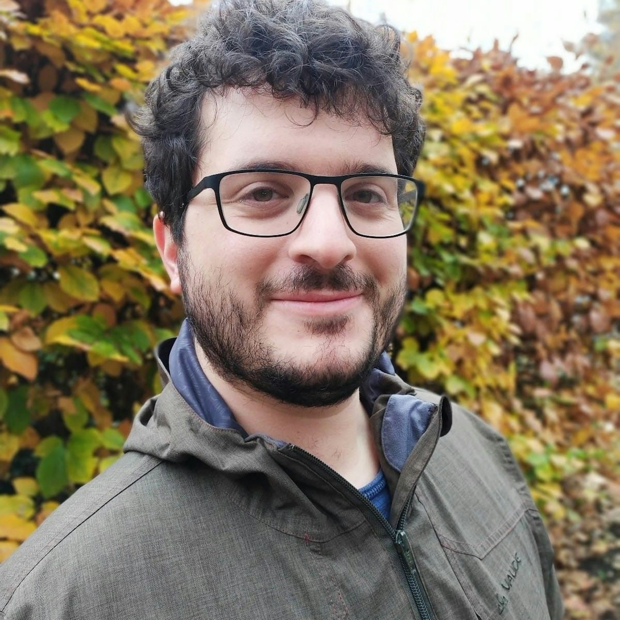 Politologe Jens Wäckerle von der Uni Köln ist im Freien zu sehen, hinter ihm eine herbstlich anmutende Hecke.