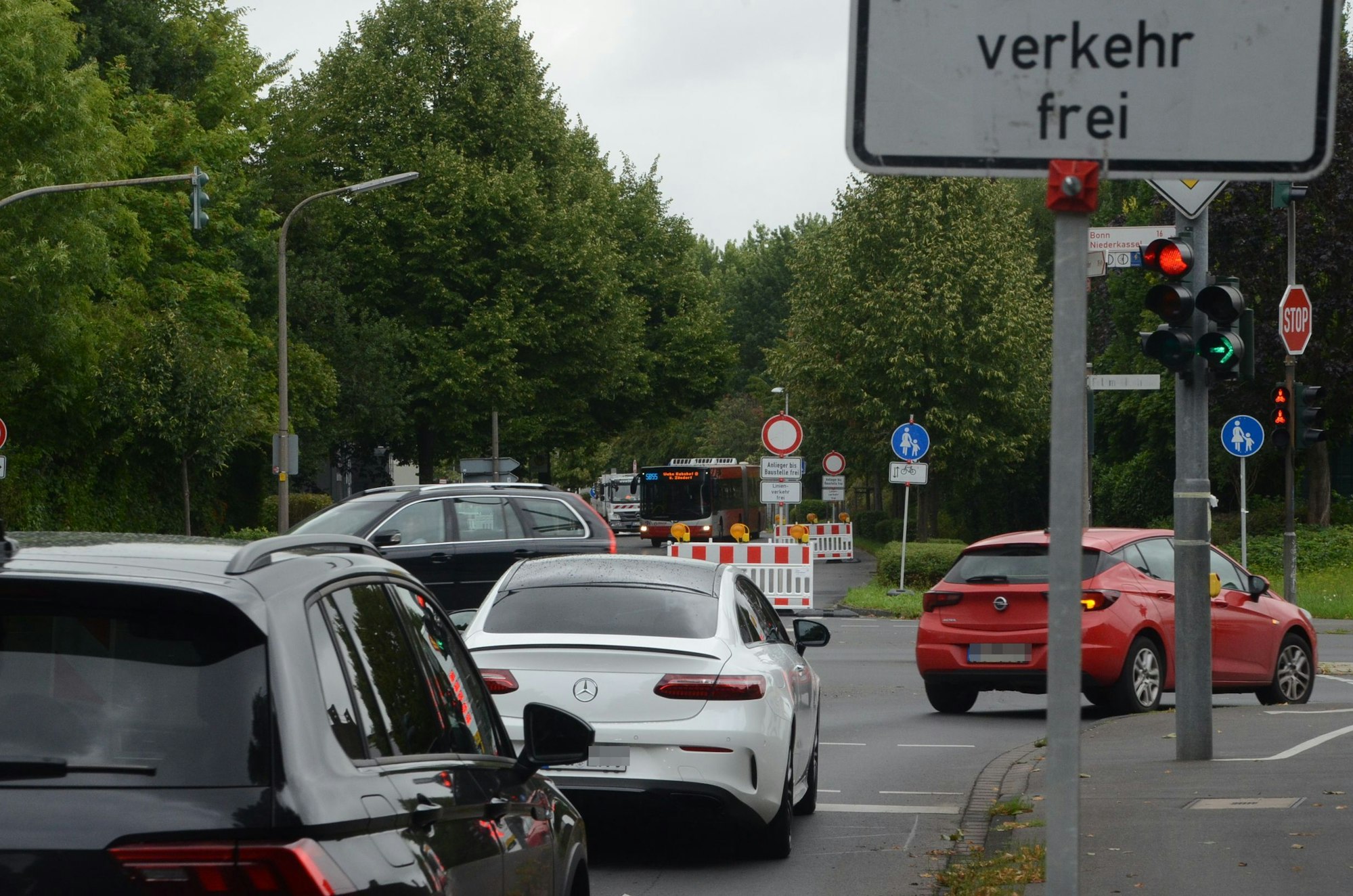 An einer Kreuzung biegen Autos nach rechts ab. Die Fahrbahn geradeaus ist von einem Absperrzaun blockiert.
