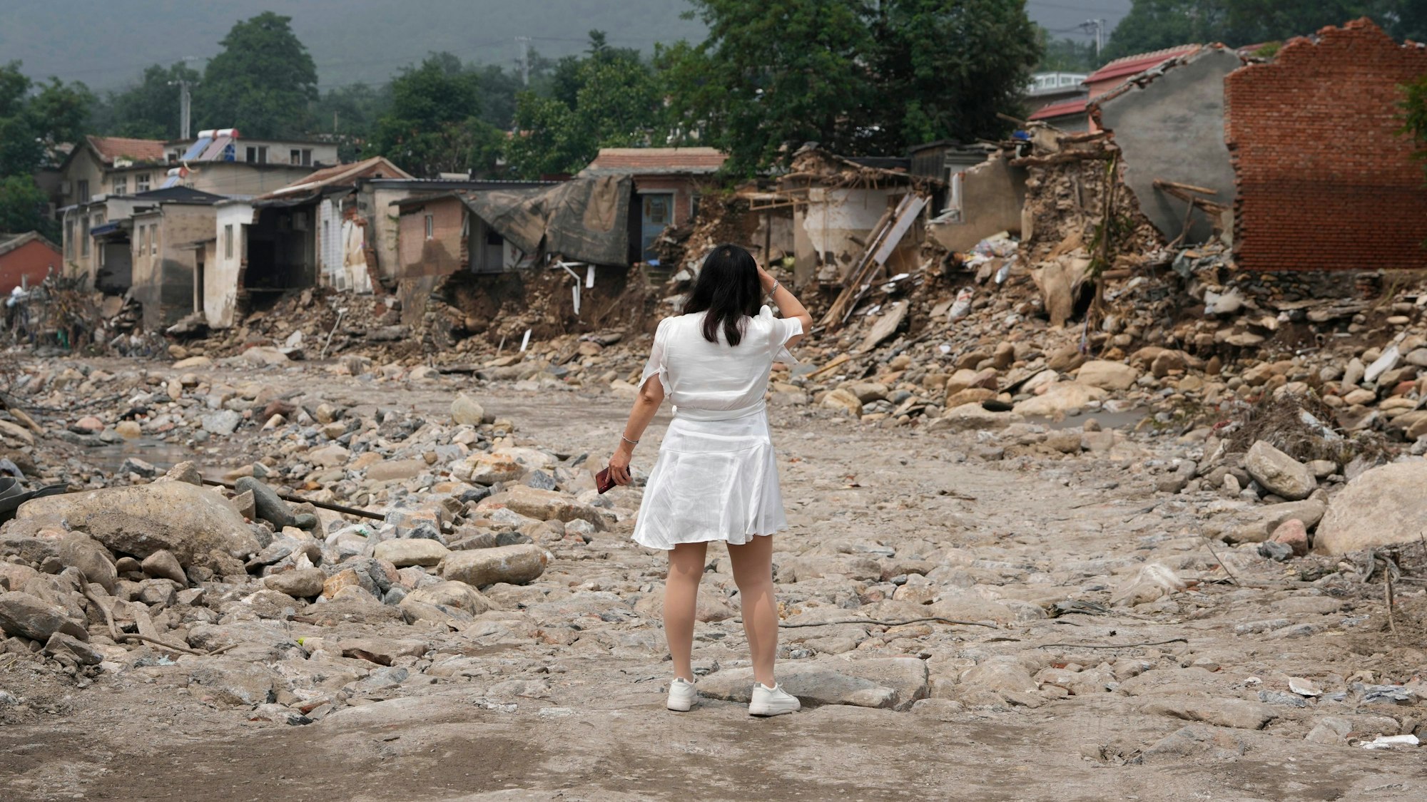 Zerstörung nach Flut in China: Eine Frau sucht nach den Überresten ihres Hauses, nachdem das Hochwasser das Dorf Nanxinfang nahe Peking erfasst hat.