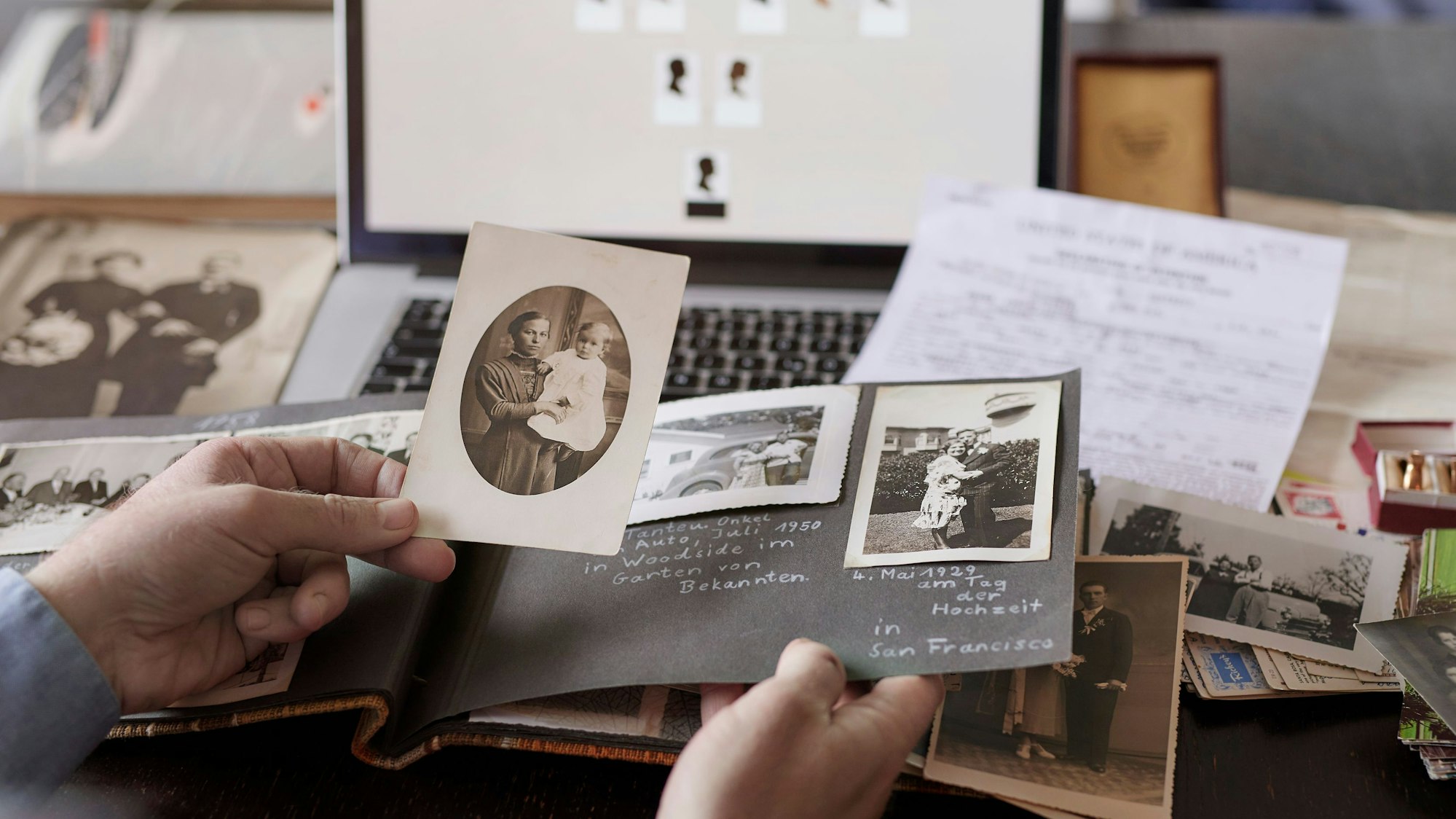 Ein Mann sitzt am Tisch und recherchiert Familienmitglieder am Computer für einen Stammbaum.