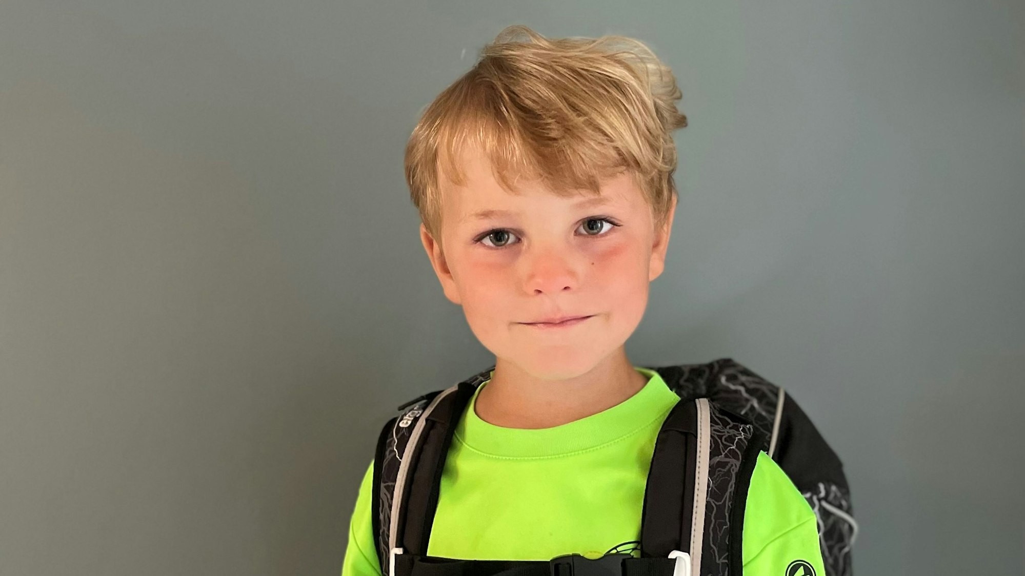 Johann Schlicht (6) guckt in die Kamera. Er trägt seine Schultasche auf dem Rücken.