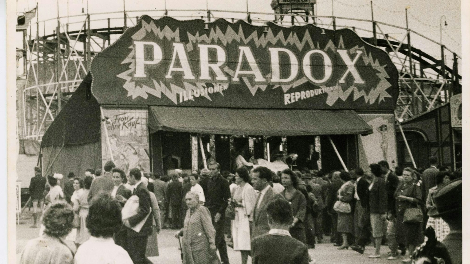 Ein altes Foto in Schwarz-Weiß zeigt eine Schaubude auf einem Jahrmarkt.