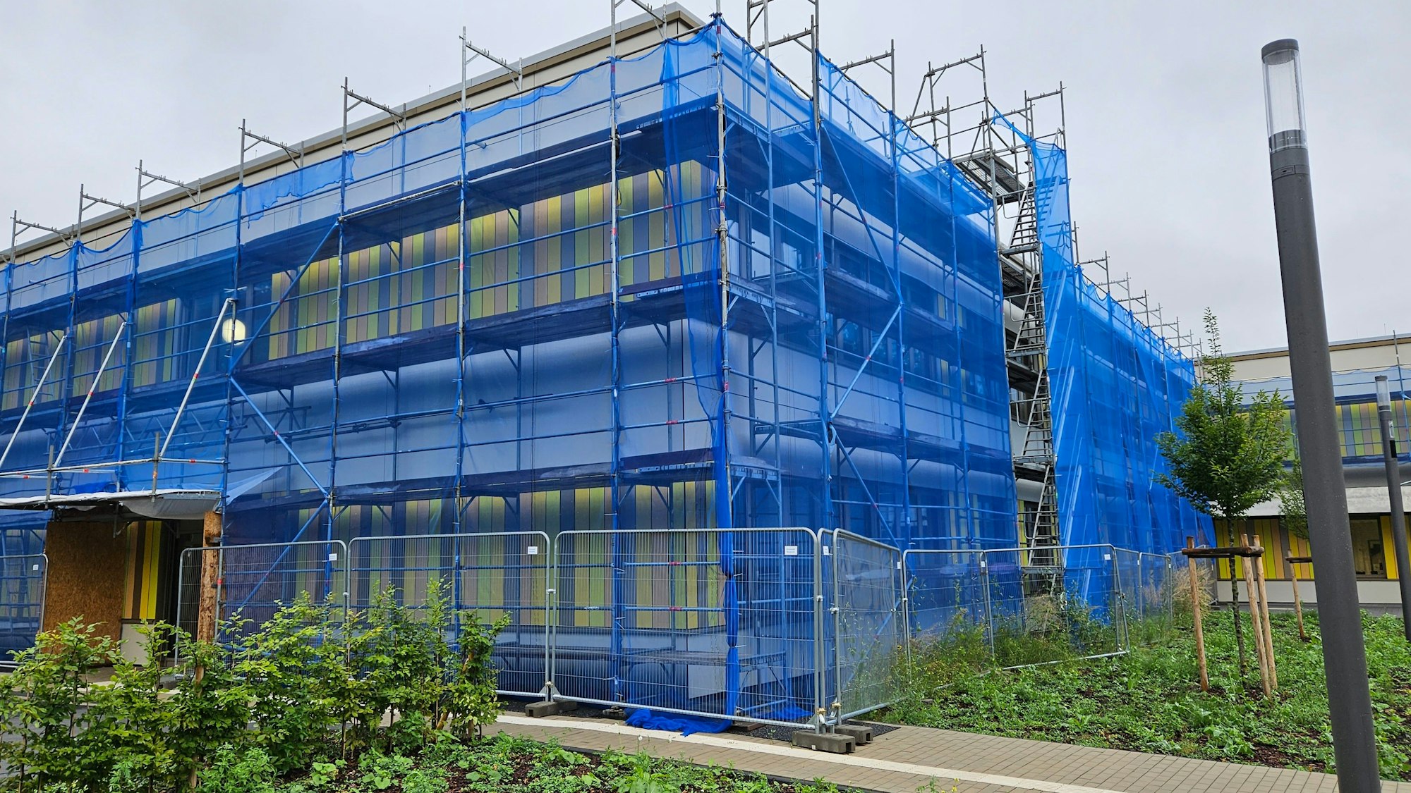 Das Foto zeigt die eingerüstete und mit blauen Netzen geschützte Fassade der Fortunaschule in Bergheim.