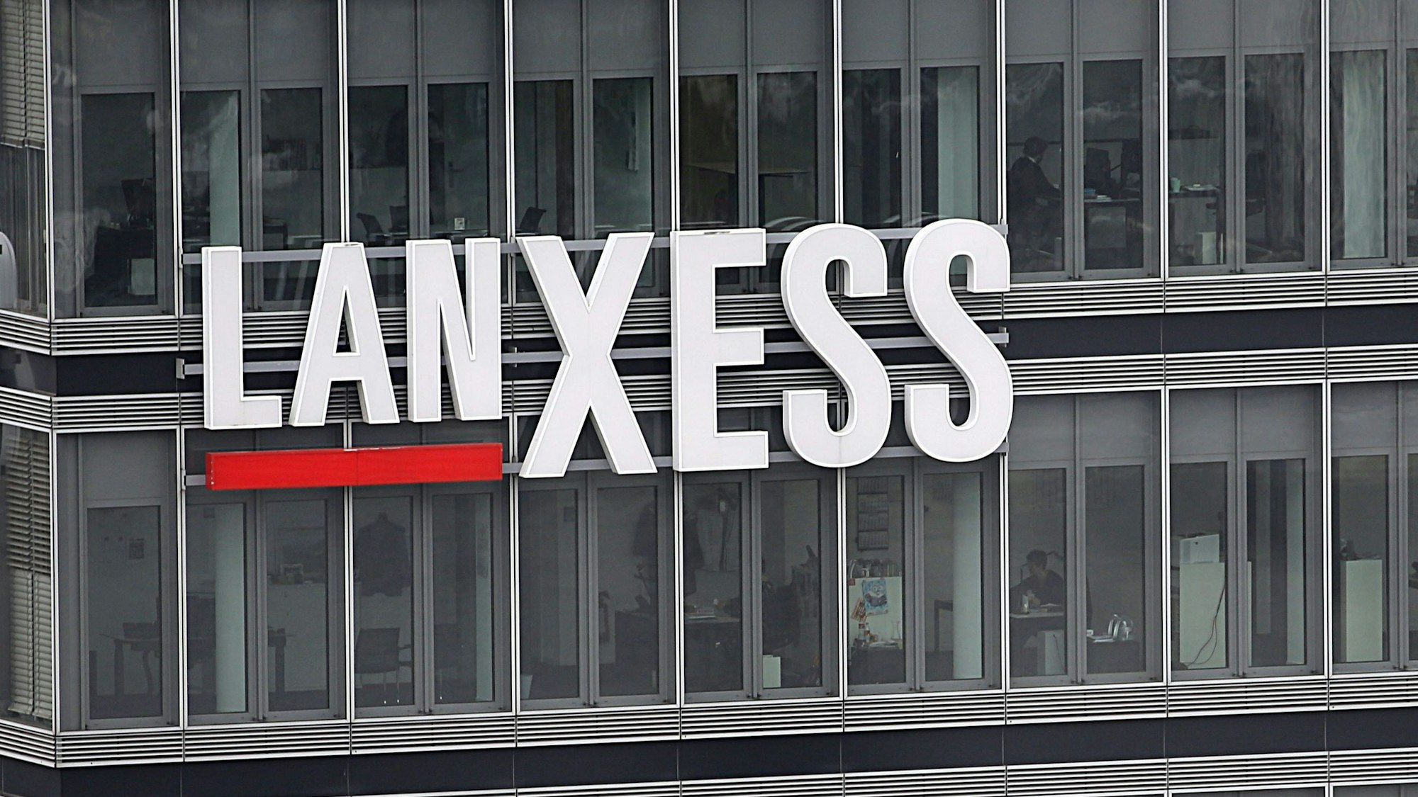 Blick auf die Zentrale des Chemiekonzerns Lanxess in Köln: Der Schriftzug Lanxess hängt auf der Glasfassade.
