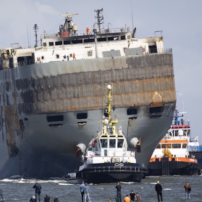 Der havarierte Nordsee-Frachter „Fremantle Highway“ wird von mehreren Schleppern in den Hafen von Eemshaven geschleppt. Das Schiff ist schwer beschädigt und in eine Richtung geneigt.