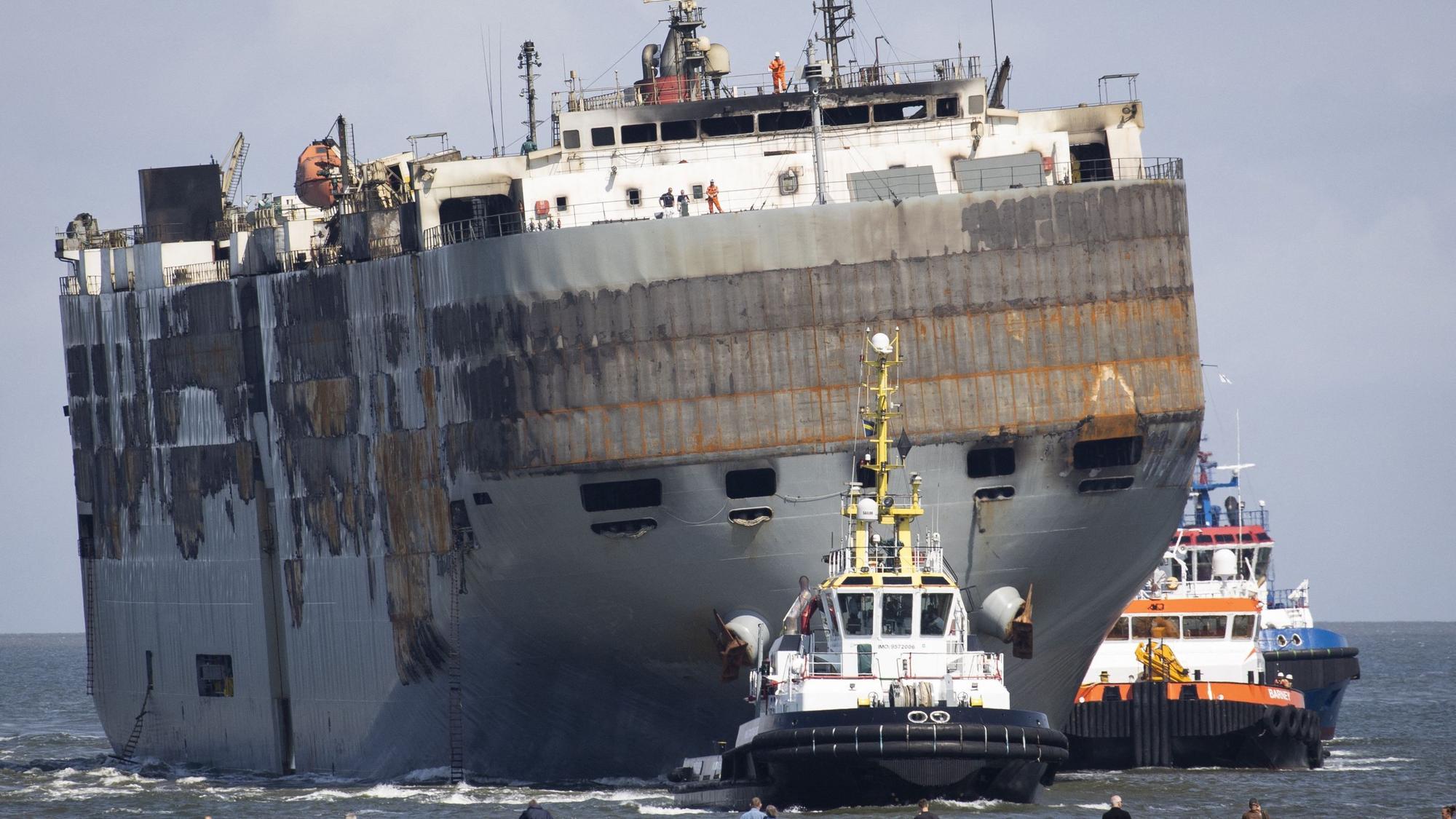 Der havarierte Nordsee-Frachter „Fremantle Highway“ wird von mehreren Schleppern in den Hafen von Eemshaven geschleppt. Das Schiff ist schwer beschädigt und in eine Richtung geneigt.