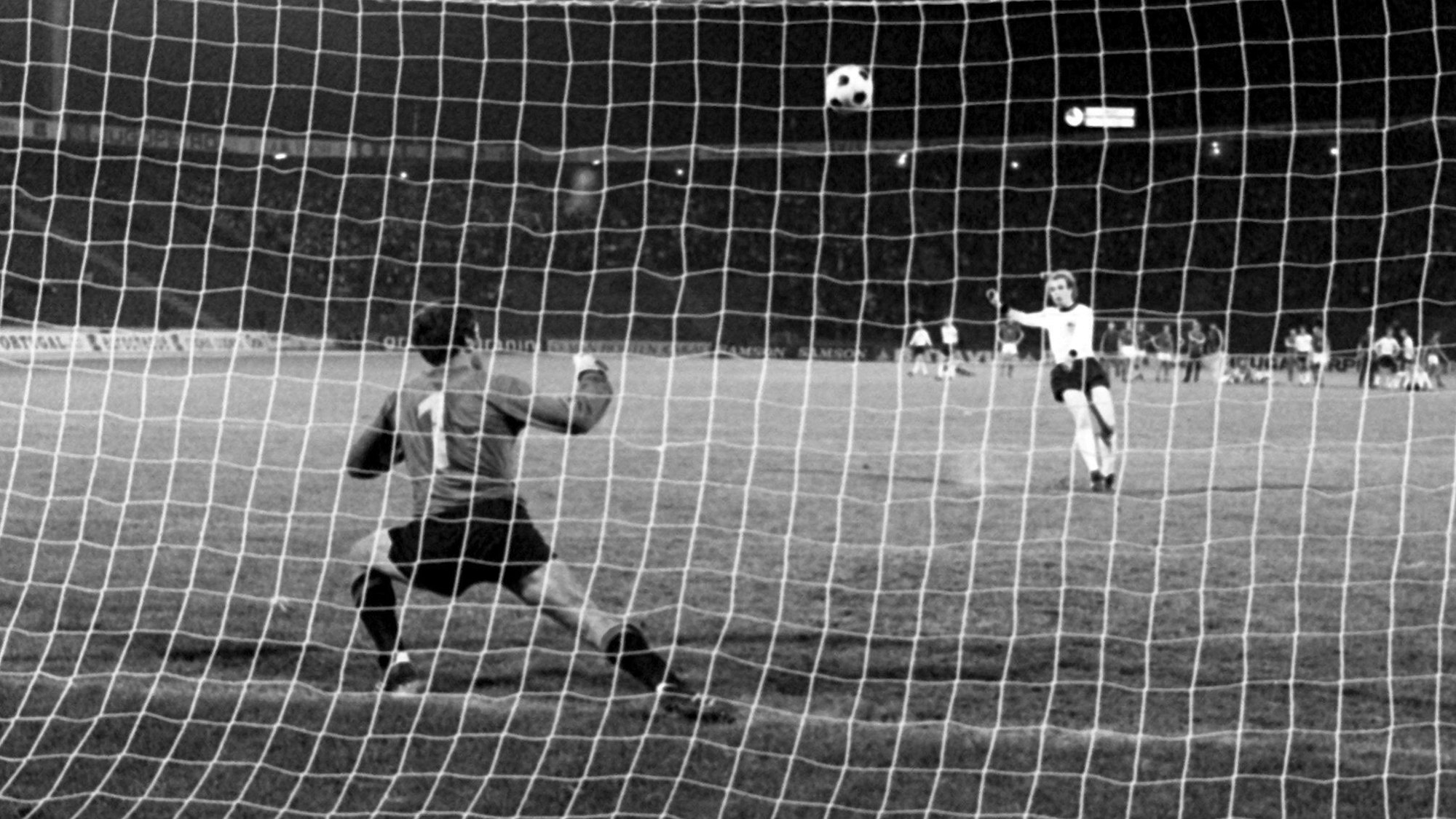 Auf dem Foto ist der verhängnisvolle Schuss im Elfmeter-Duell am 20. Juni 1976 in Belgrad im Europameisterschaftsfinale zwischen der deutschen Fußballnationalmannschaft und der CSSR zu sehen: Tschechoslowakei-Torhüter Ivo Viktor schaut gebannt zu, wie der deutsche Mittelfeldspieler Uli Hoeneß den Ball über die Latte schießt.