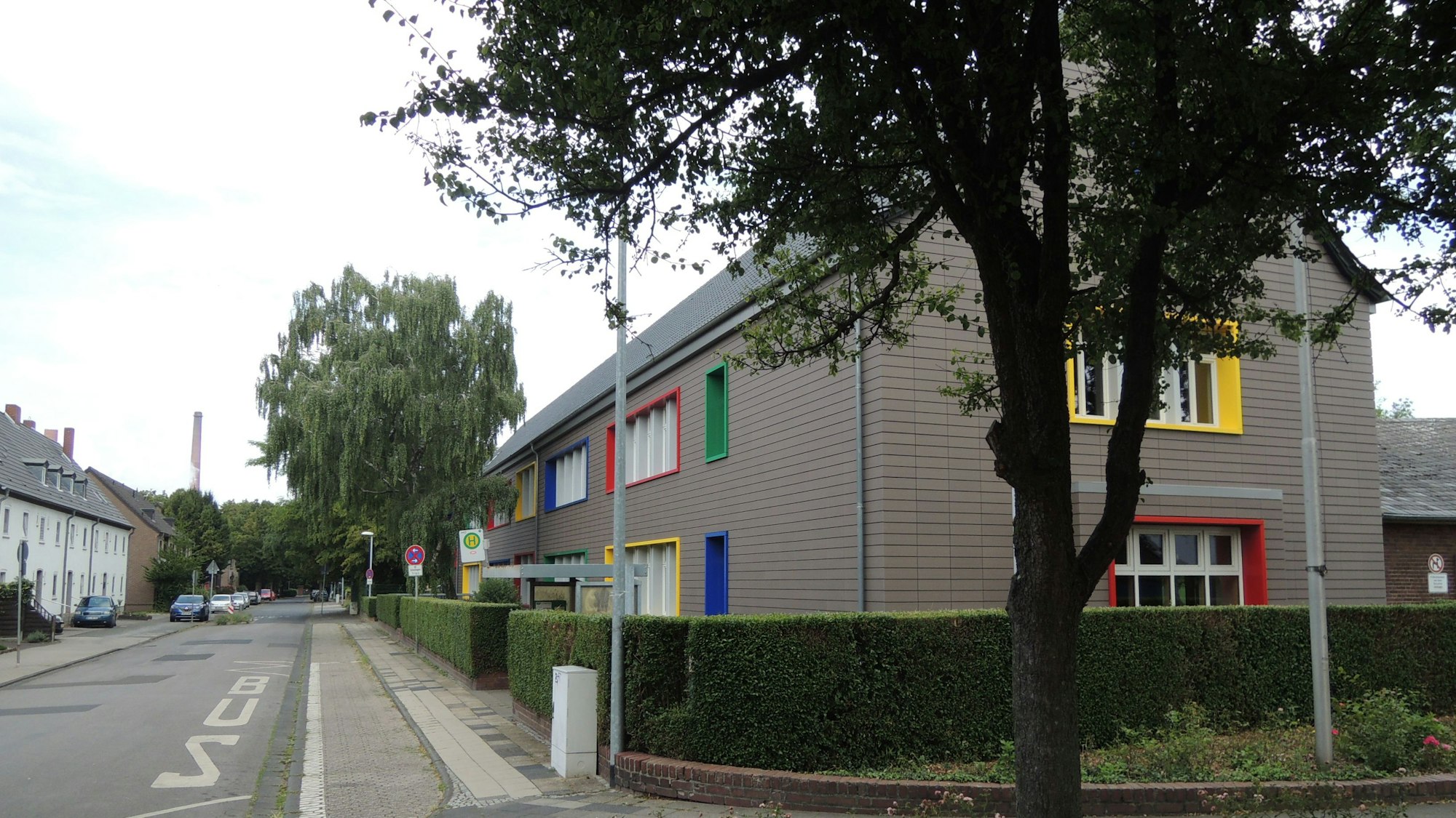 Ein Gebäude mit bunt umrahmten Fenstern steht an der rechten Seite einer Straße.