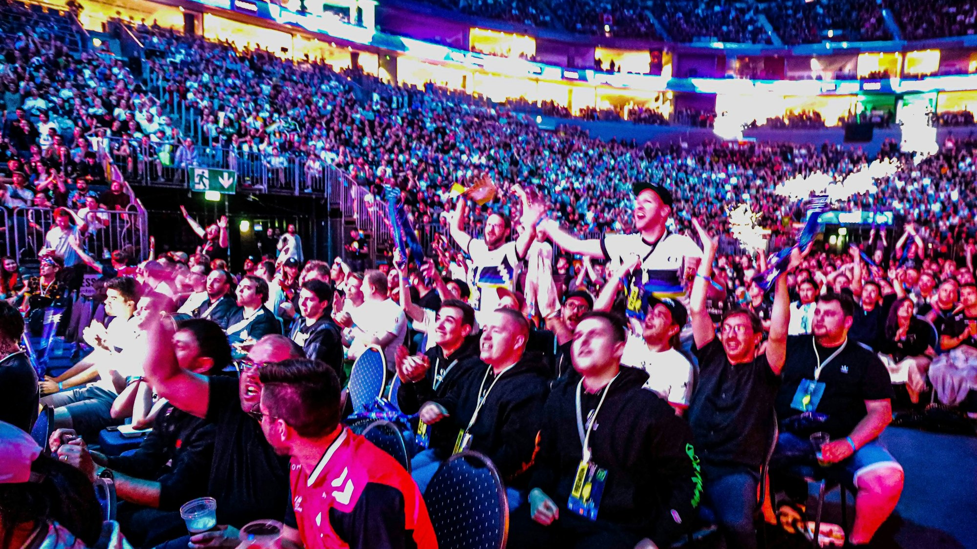 Männer sitzen auf Stühlen in der Lanxess-Arena und jubeln.