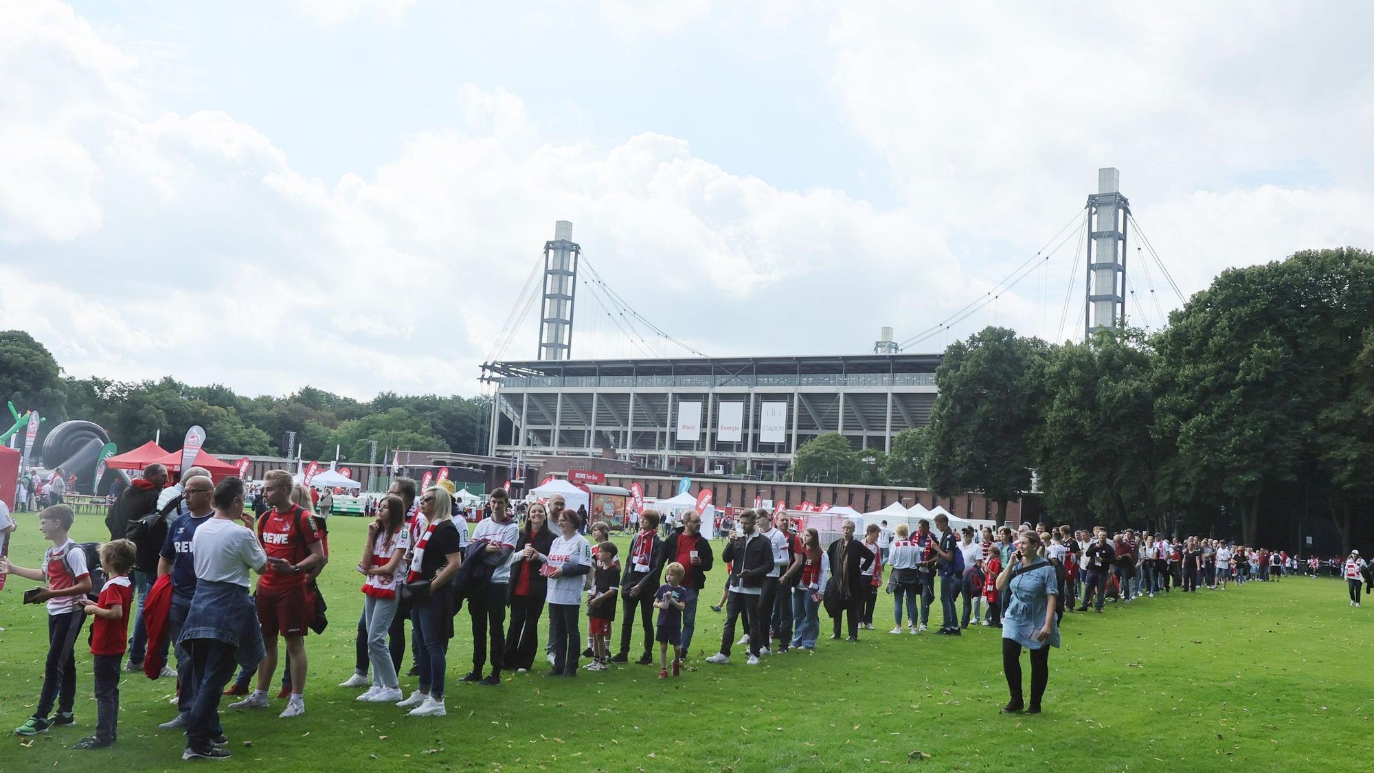 Zahlreiche Fans stehen auf einer Wiese für Autogramme der FC-Spieler Schlange.