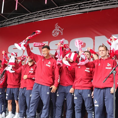 Die Mannschaft des 1. FC Köln singt die FC-Hymne auf einer Bühne.