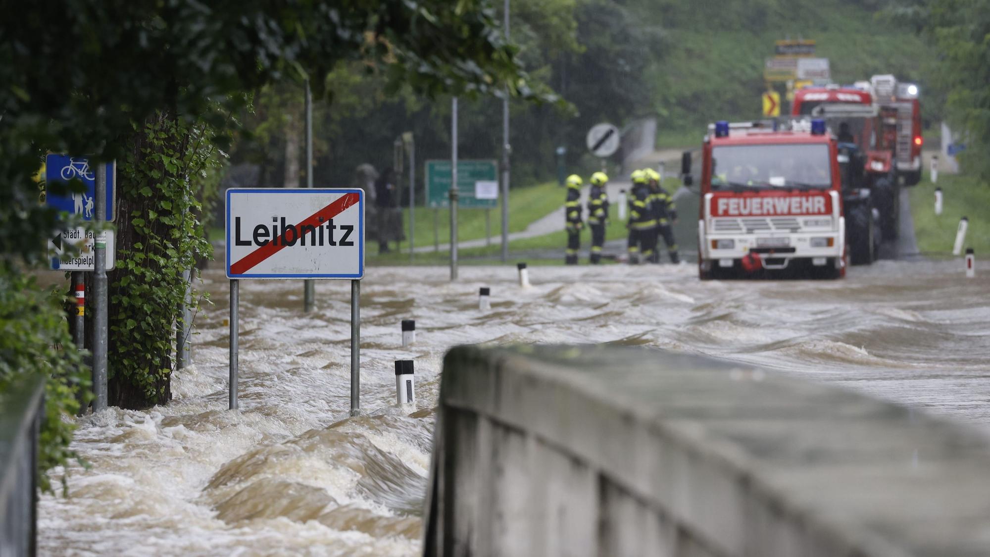 Feuerwehrwagen stehen vor einer überfluteten Brücke über die Sulm am Ortsausgang von Leibnitz in der Steiermark.
