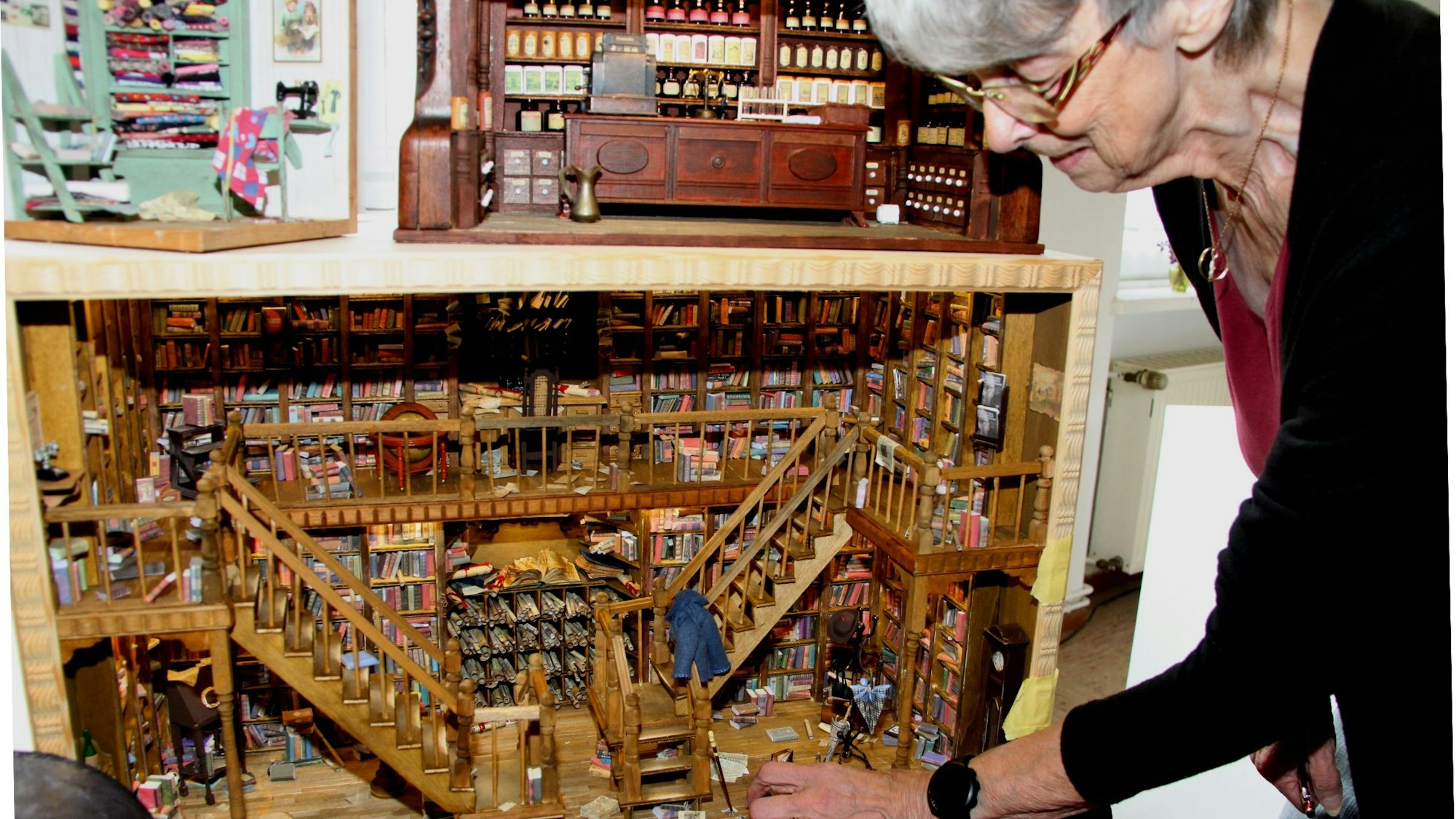 Das Bild zeigt die Künstlerin Gerda Weitz an einer Miniatur-Bibliothek, die sie aus s 3500 Einzelteilen angefertigt hat.
