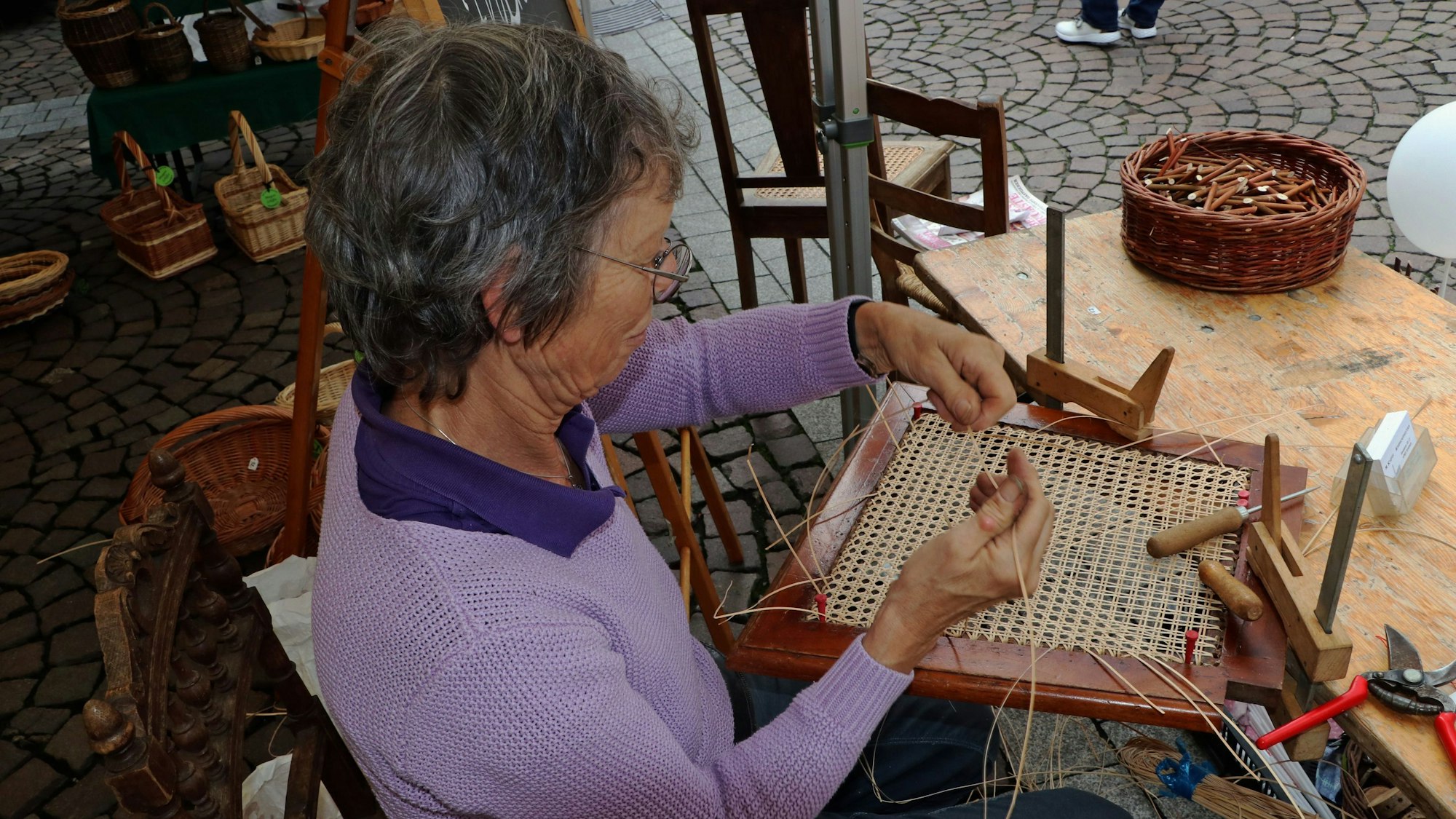 Korbmacherin Margirit Schiffer arbeitet an einer Sitzfläche für einen Stuhl aus Korb.
