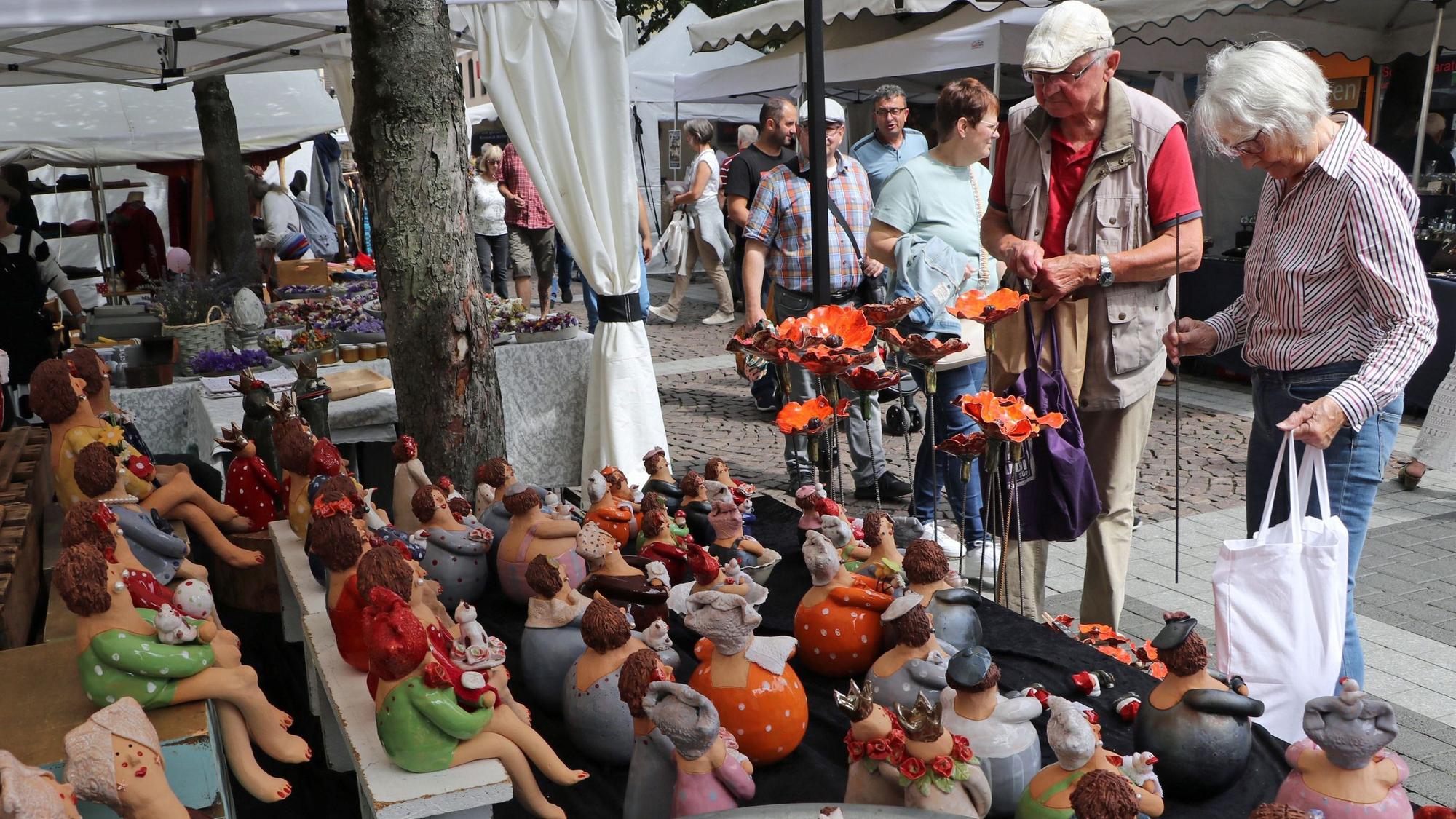 Eine Frau und ein Mann betrachten die vielen Keramik-Figuren.