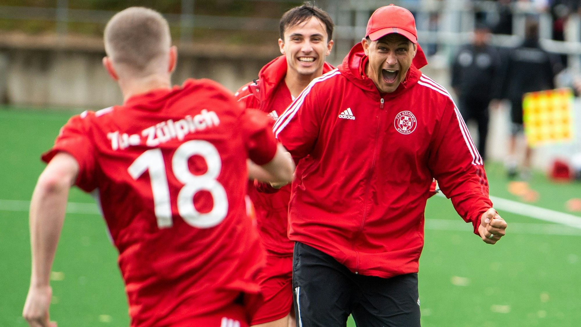 Das Bild zeigt Zülpichs Trainer David Sasse, der auf Torschütze Dominik Spies zuläuft, nachdem dieser ein Tor erzielt hat.