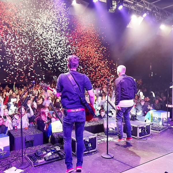 Das Bild zeigt von hinten Musiker der Kölner Band Kasalla. Aus einer Kanone wird rot-weißes Konfetti auf die Zuschauer geschossen.
