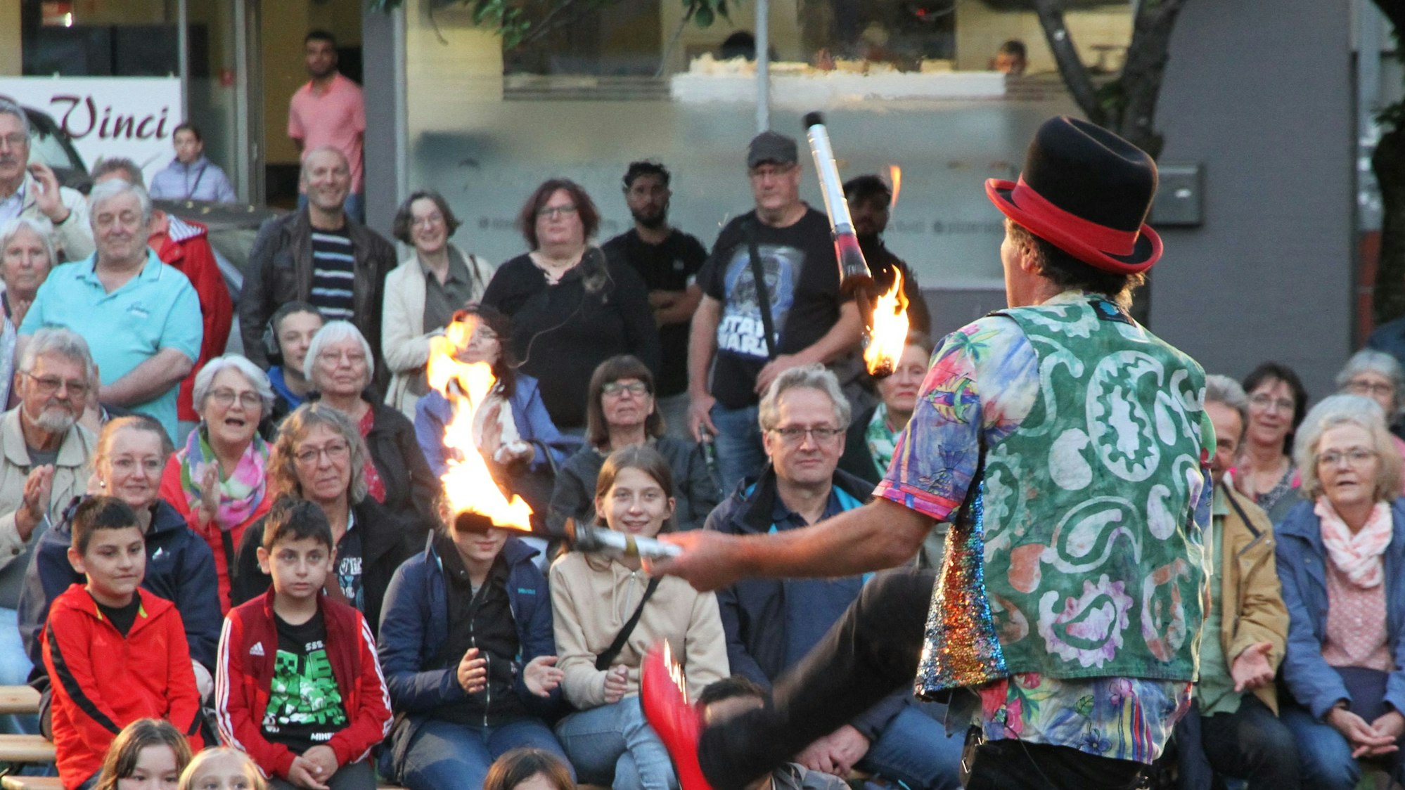 Ein Gaukler jongliert mit brennnden Kegeln.