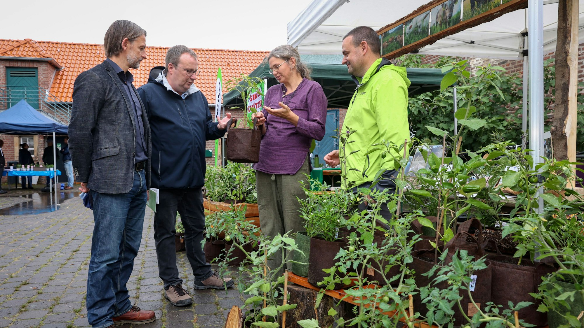 Drei Männer und eine Frau an einem Stand mit Pflanzen.