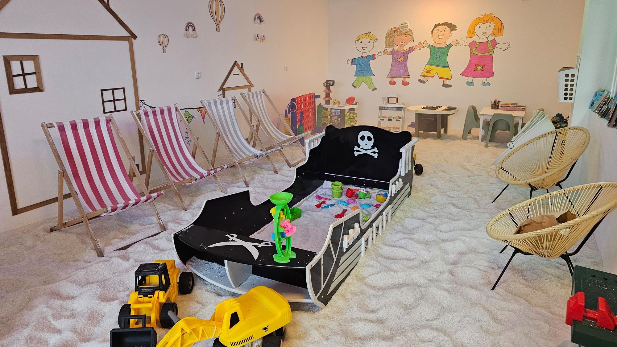 In einem Spielzimmer liegt weißer Sand auf dem Boden.