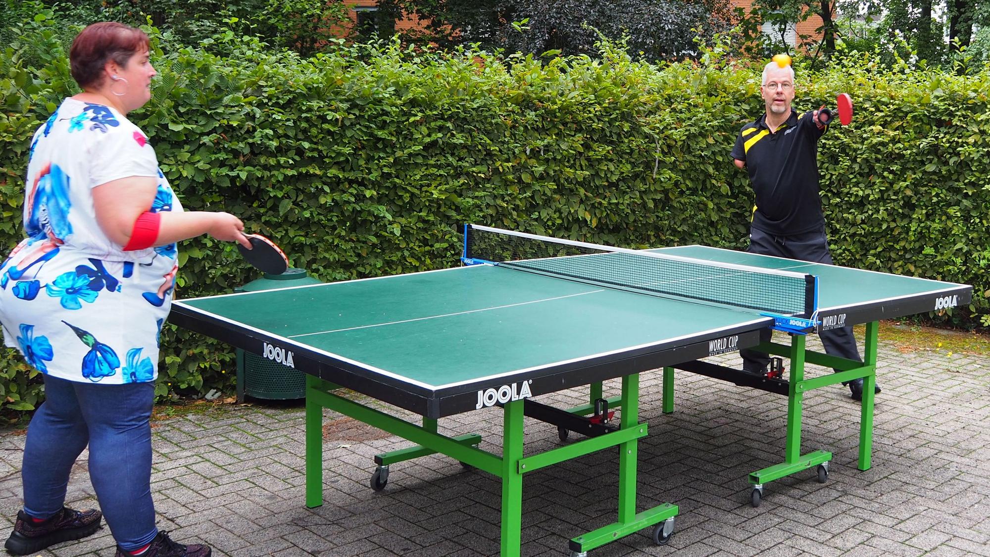Ein Mann mit verkürzten Armen und eine Frau spielen Tischtennis.