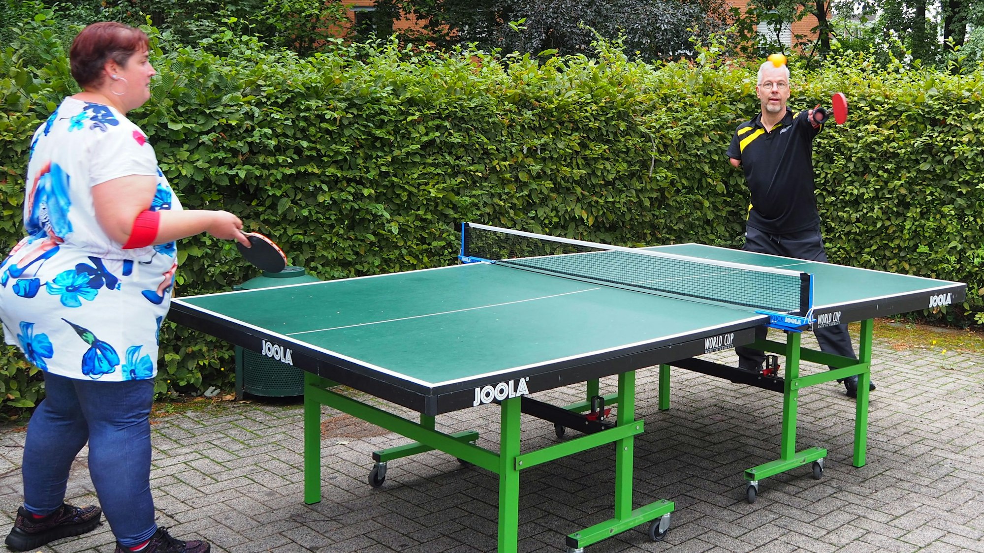 Ein Mann mit verkürzten Armen und eine Frau spielen Tischtennis.